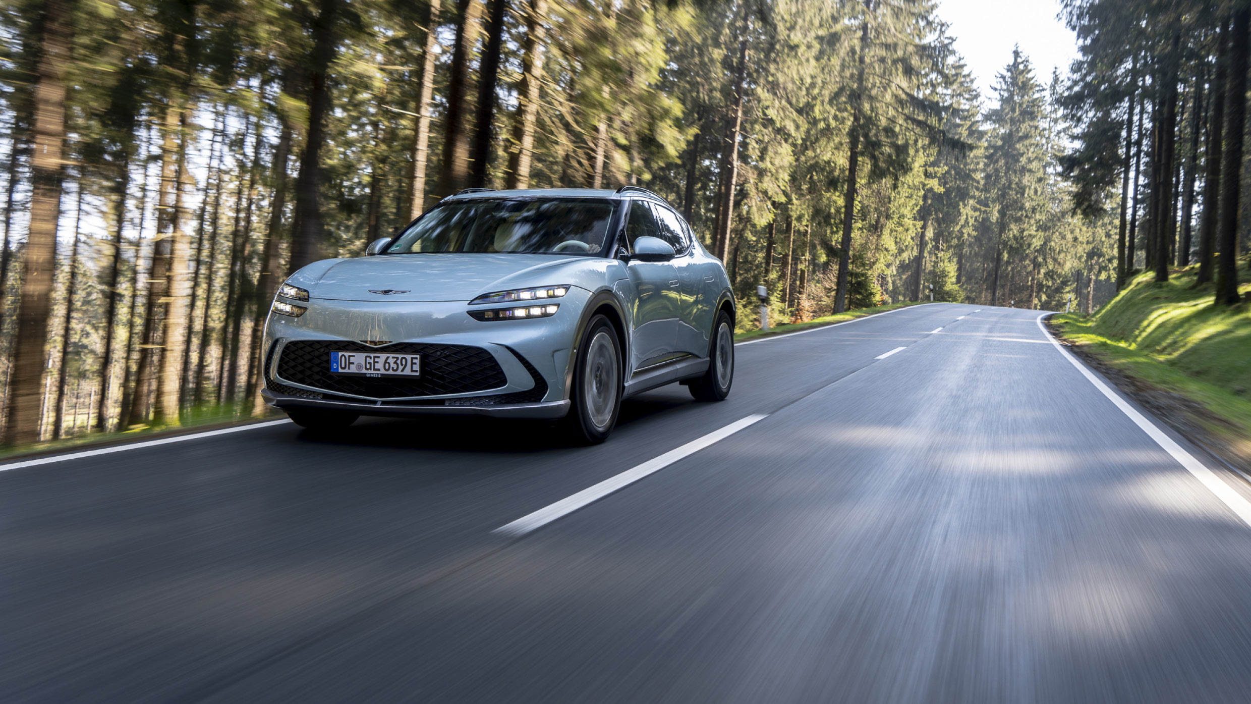 GV60이 유럽의 숲 속 도로를 주행하는 모습