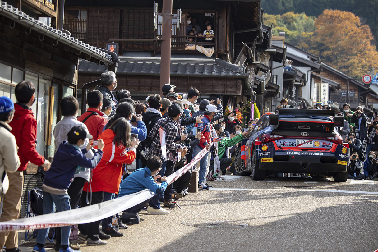 A WRC race car standing in the cheers of the crowd