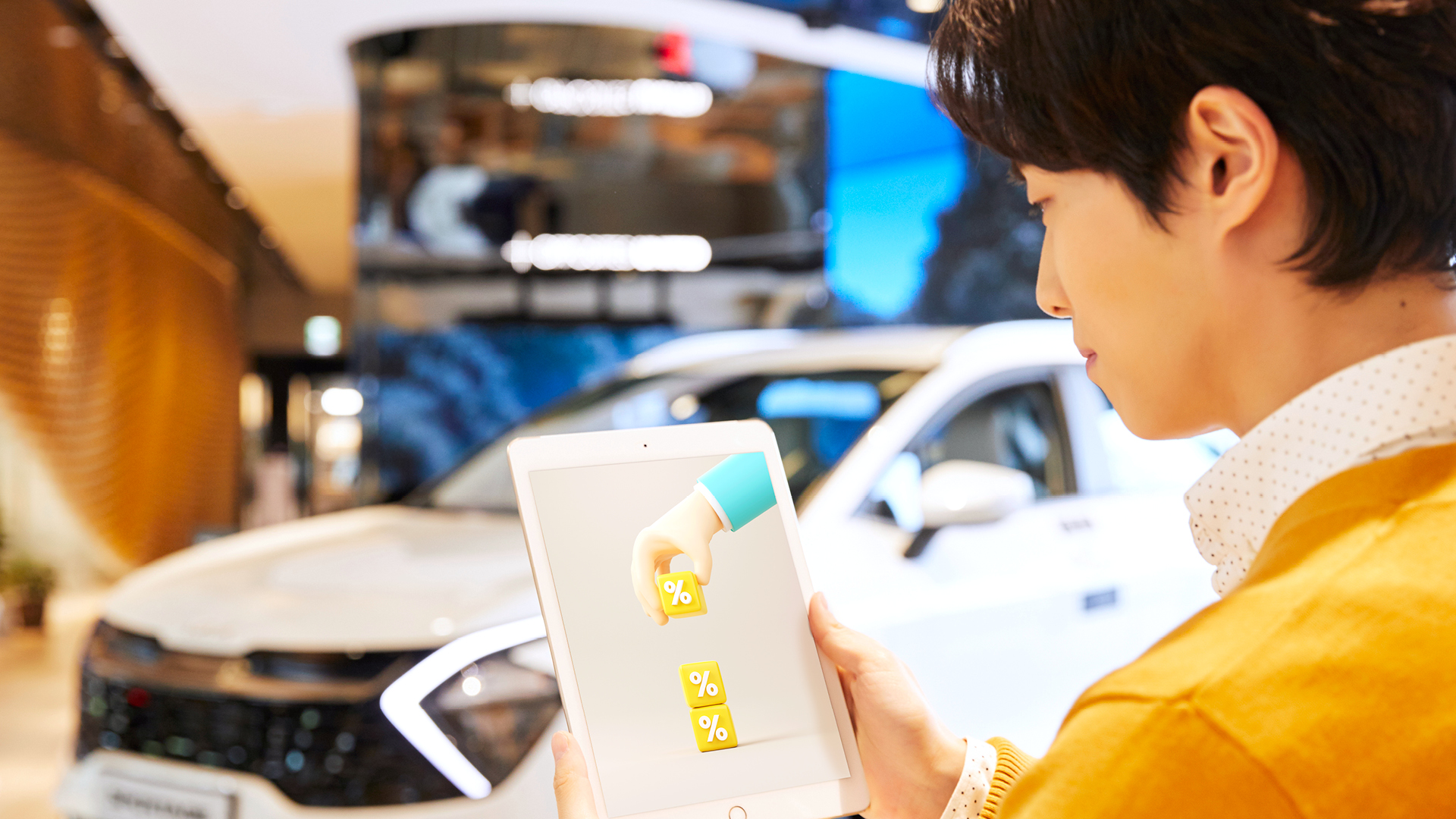 자동차 매장에서 태블릿피씨를 보고 있는 남자의 모습