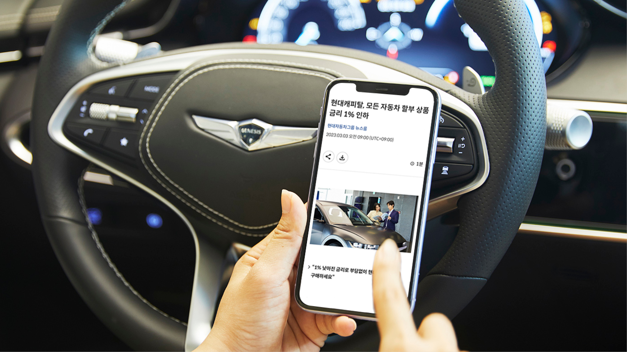 차 안에서 현대캐피탈 금리 인하 뉴스를 스마트폰으로 보고 있는 모습