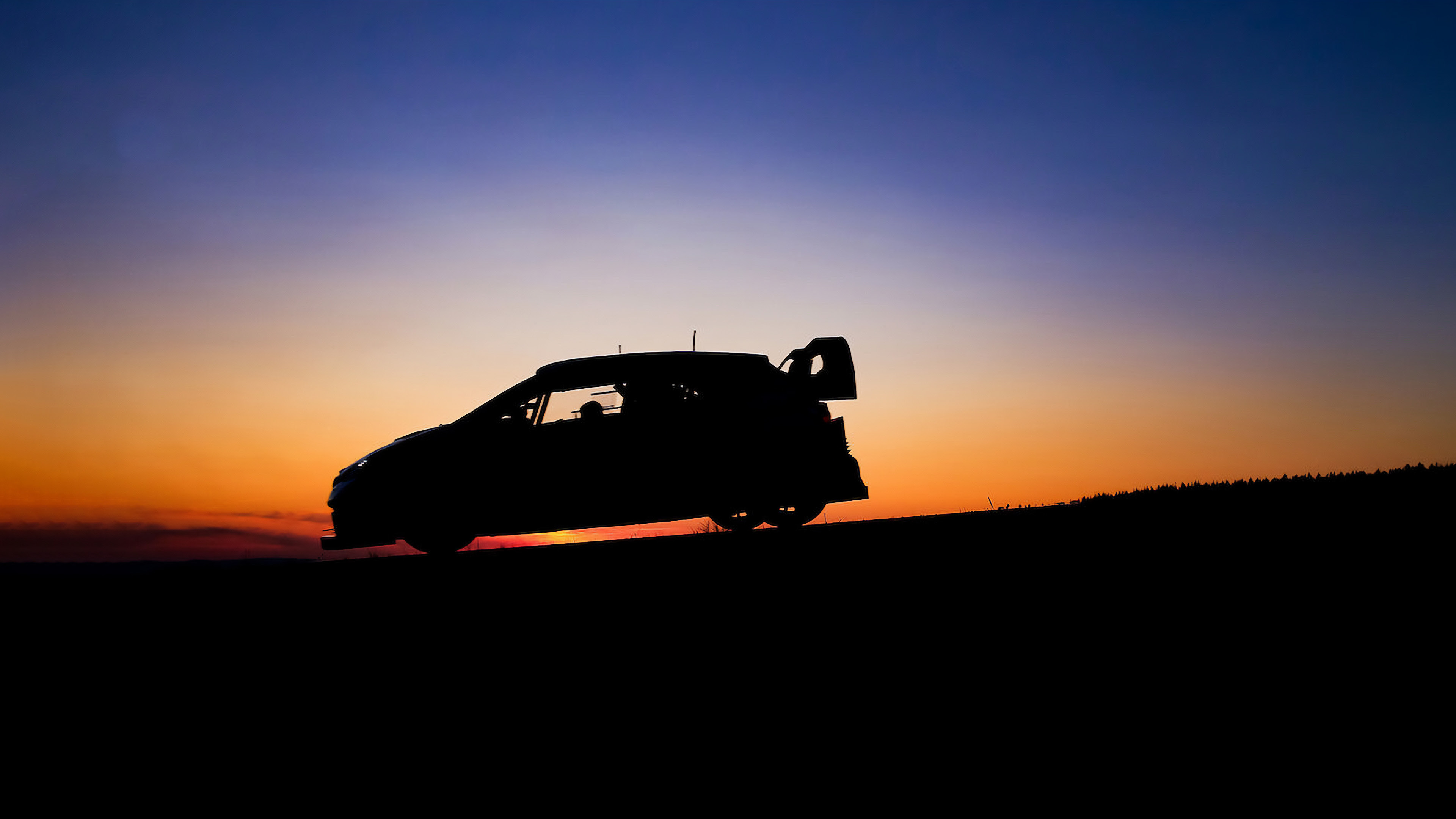 A rally car standing behind the setting sun