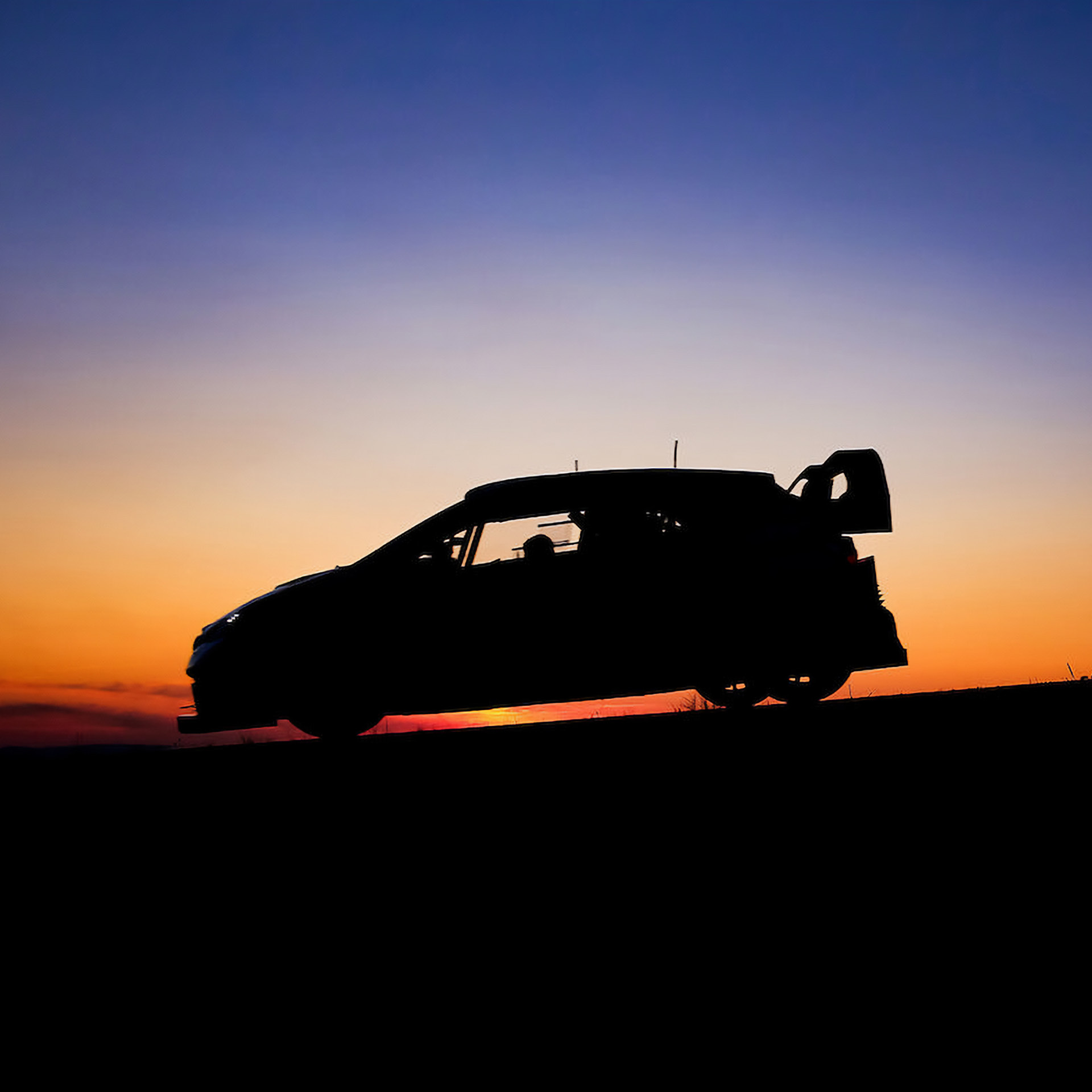 A rally car standing behind the setting sun