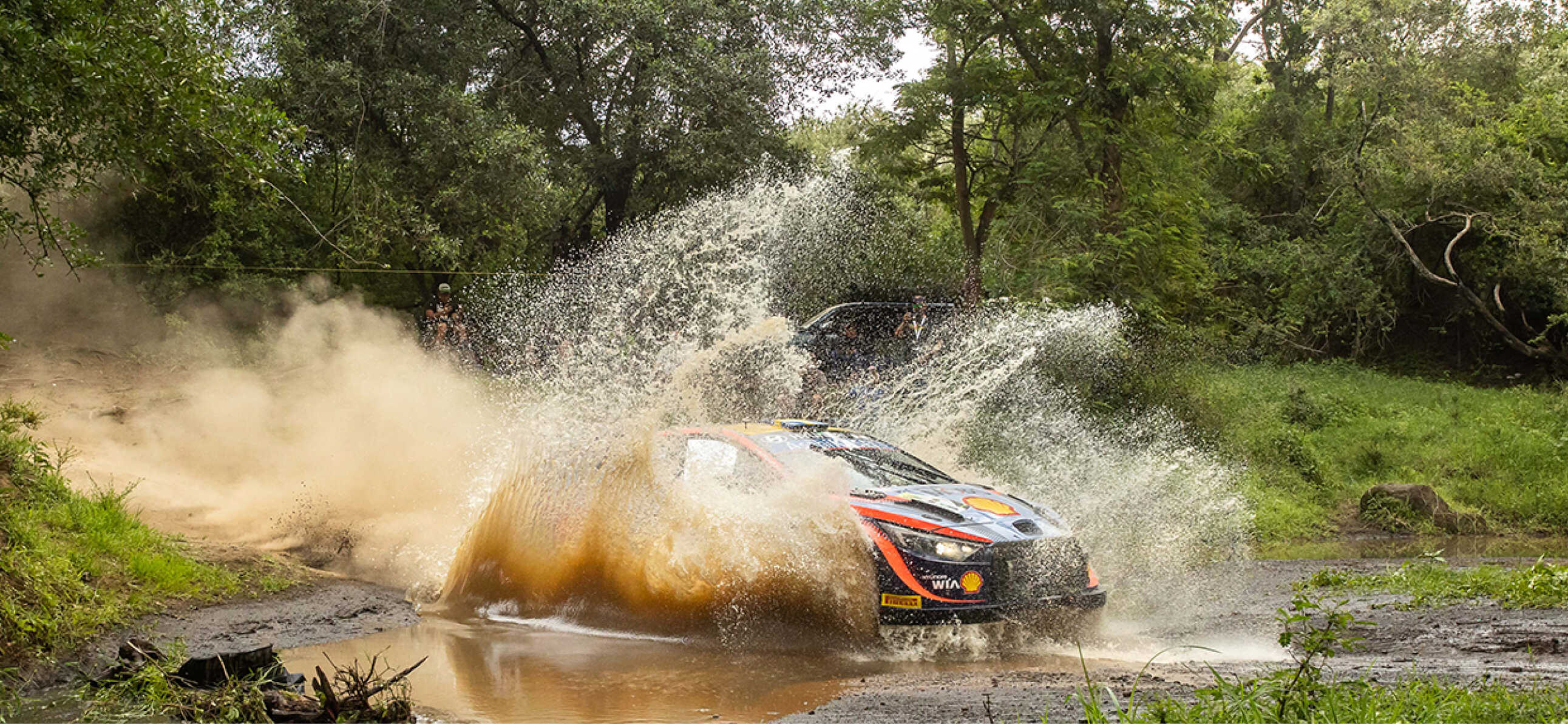 A Hyundai WRC rally car driving down a stream