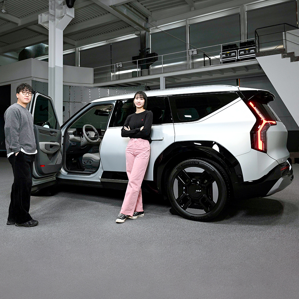 남자 연구원과 여자 연구원이 EV9 측면에 나란히 서 있는 모습