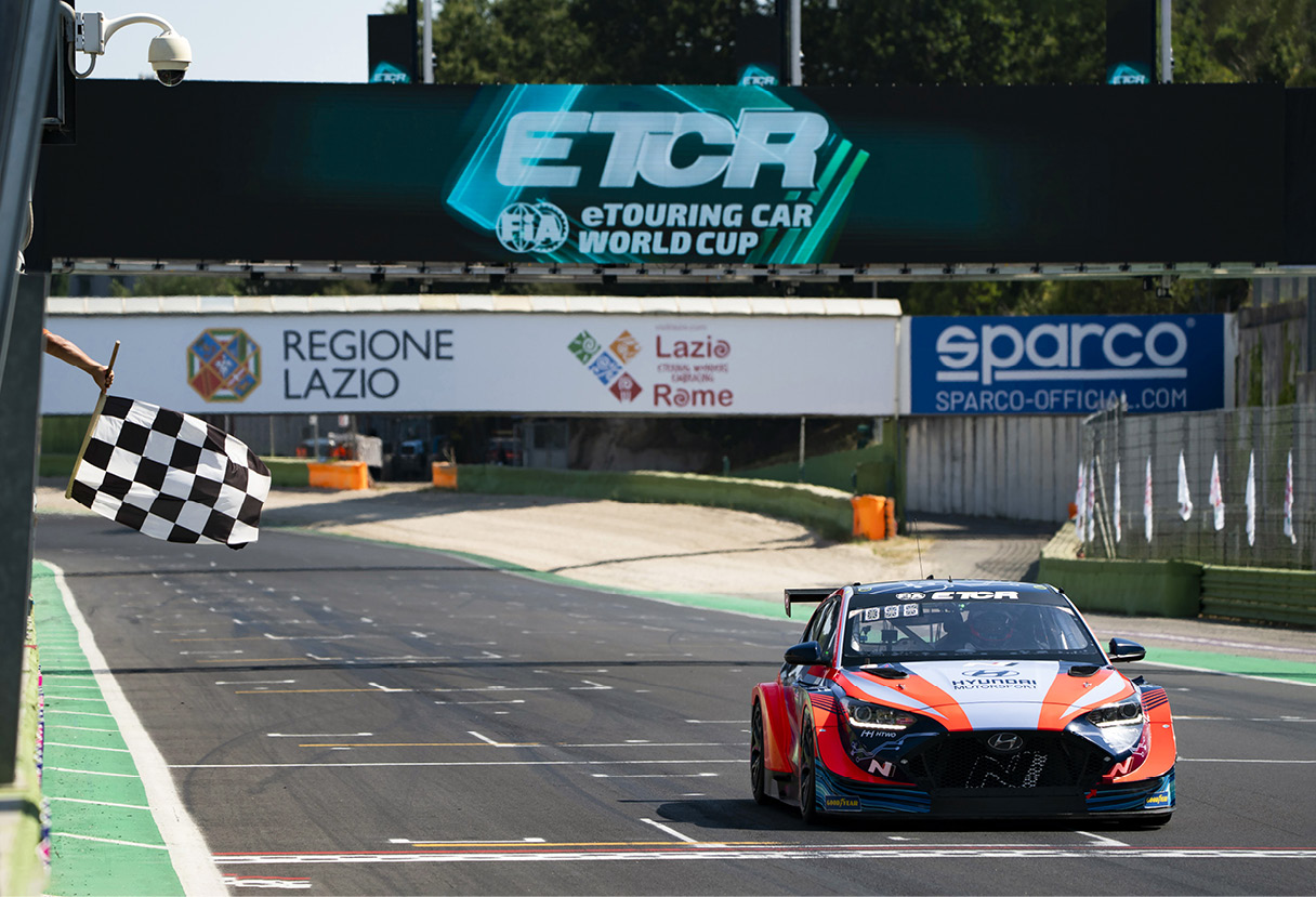 A Hyundai motorsport race car crosses the finish line under checkers
