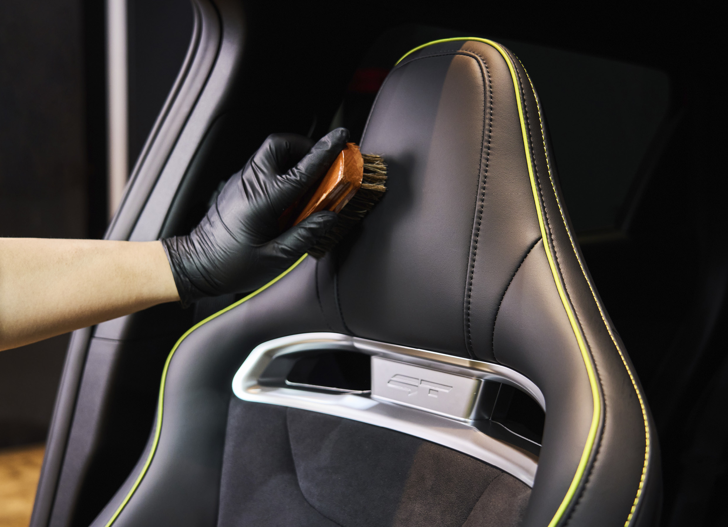 Seats are being cleaned using an indoor car wash brush