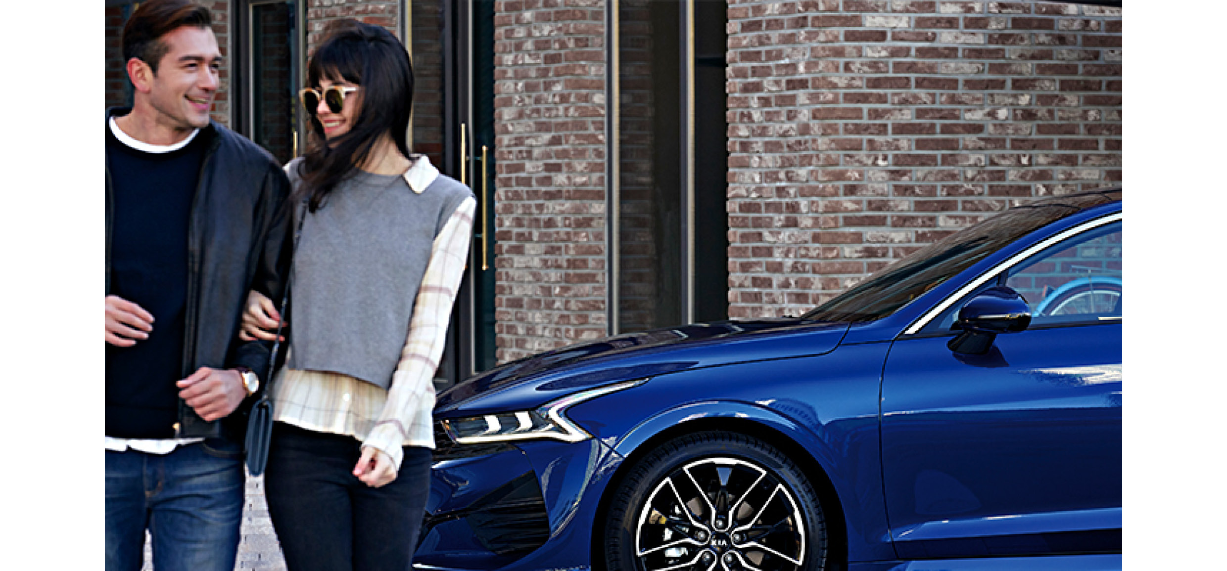 A pair of man and woman are standing with their backs to the Kia K5