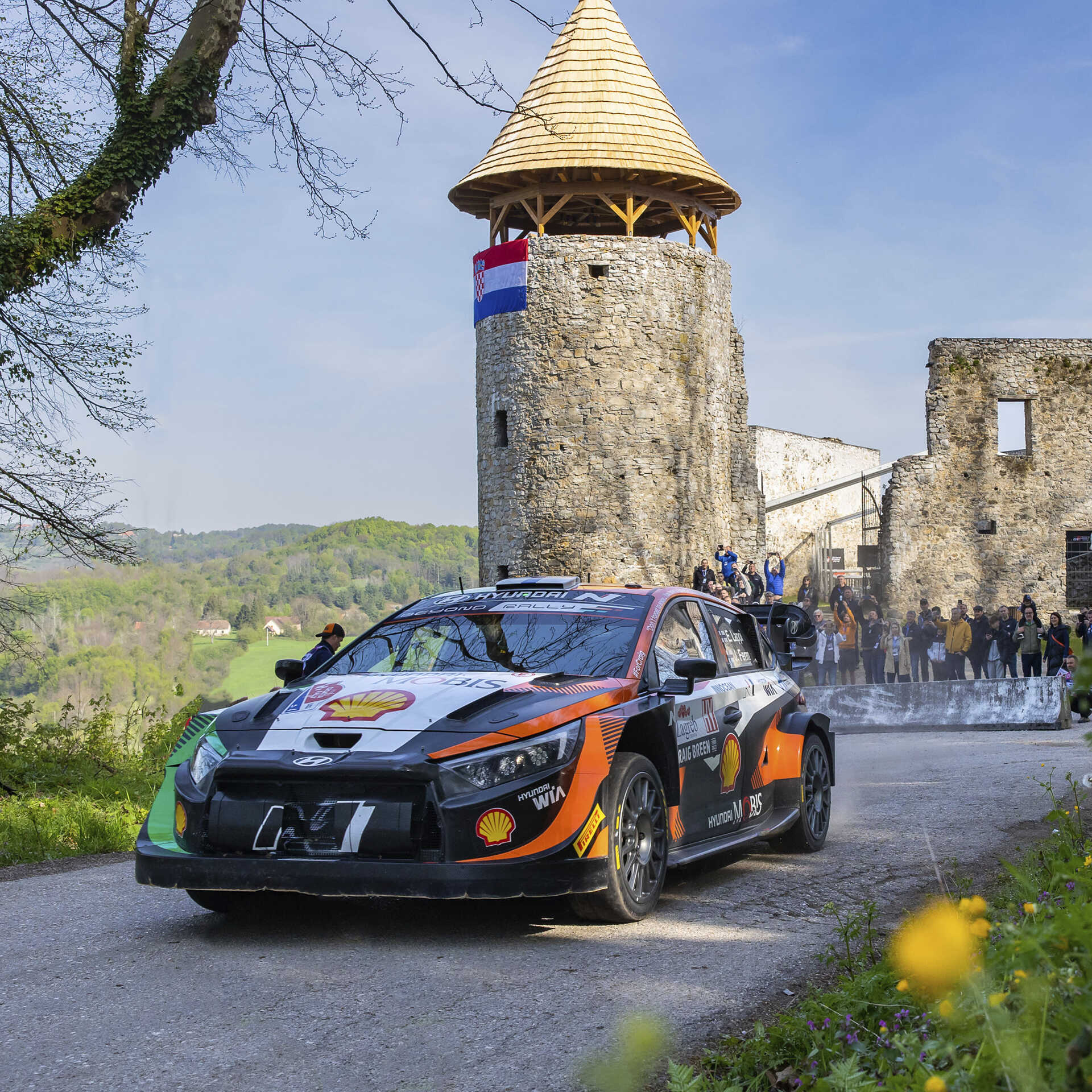 A Hyundai rally car speeding down the road in front of the castle