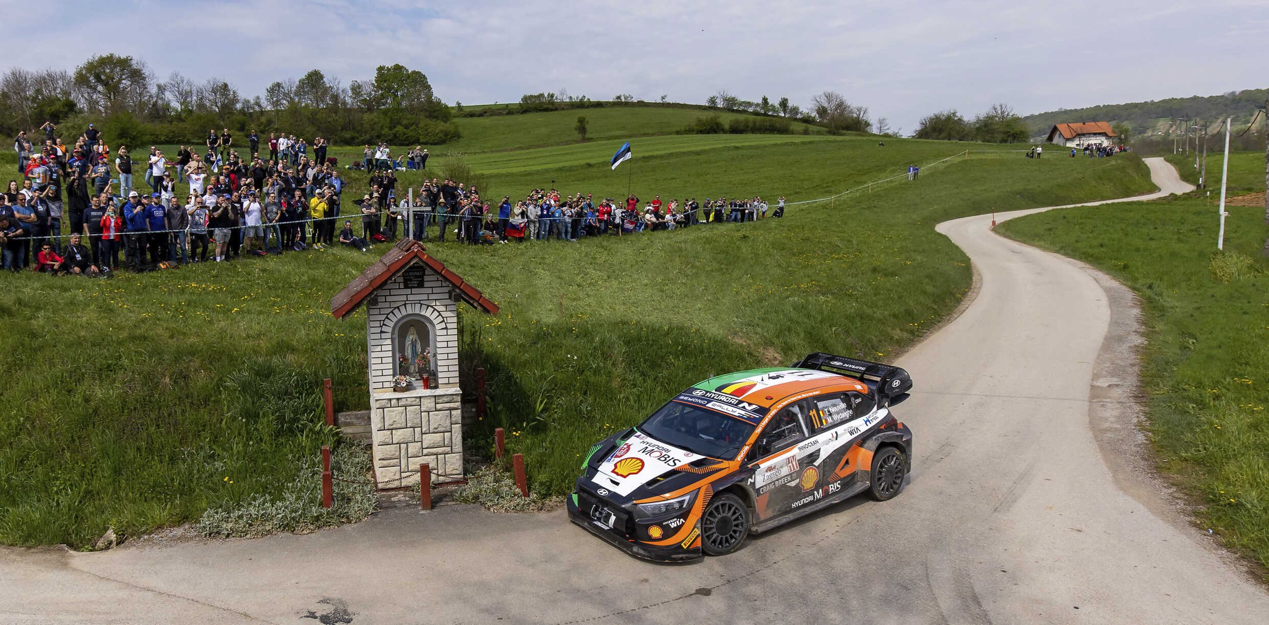 Speeding rally cars and applauding crowds