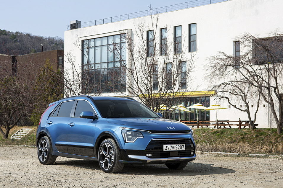 A blue Niro parked in front of a white building