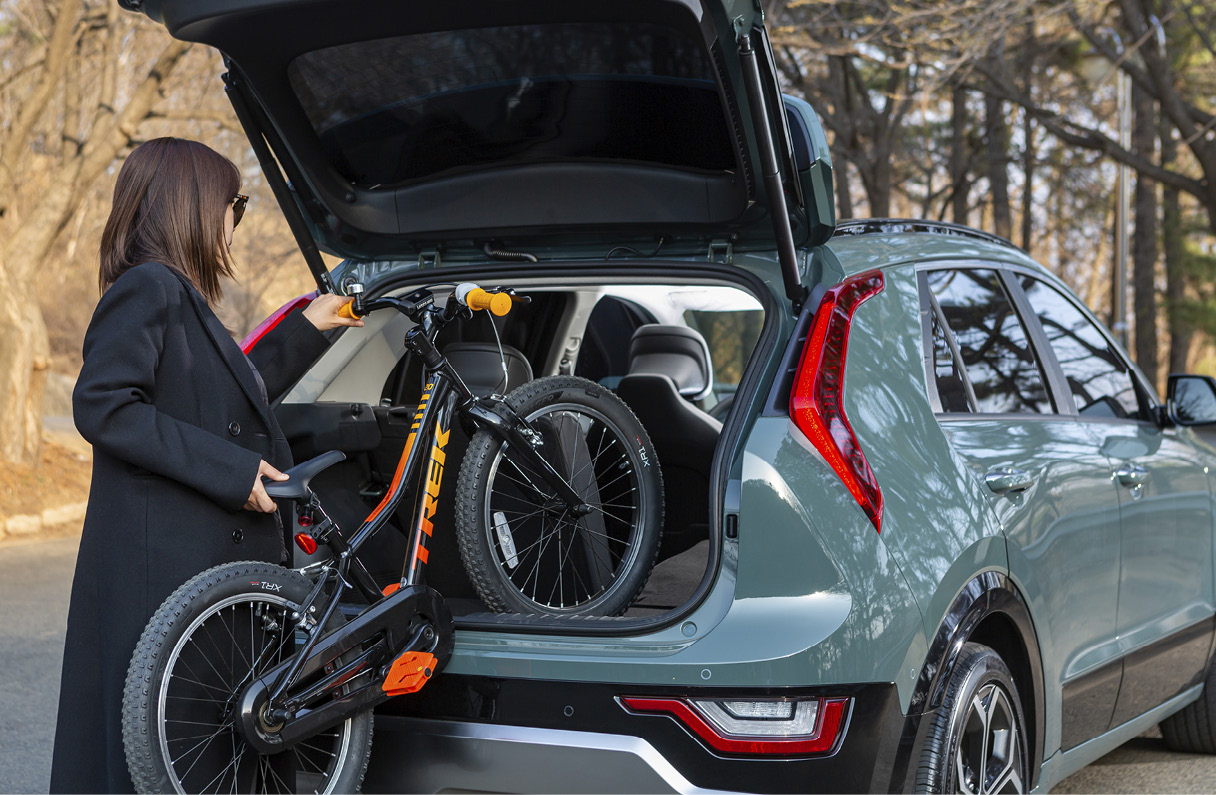 The back of a woman opening the tailgate to store her bike