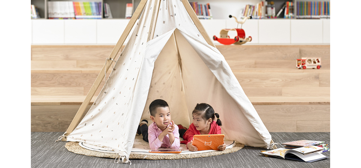 어린아이들이 바닥에 누워 책을 읽으며 즐거운 시간을 보내고 있다.