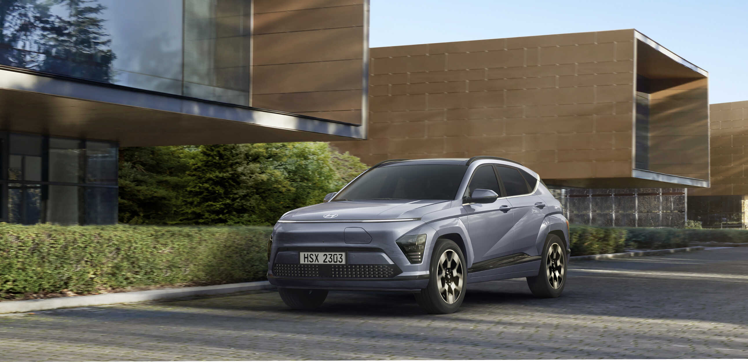 모던한 건물 사이를 달리고 있는 디 올 뉴 코나 일렉트릭