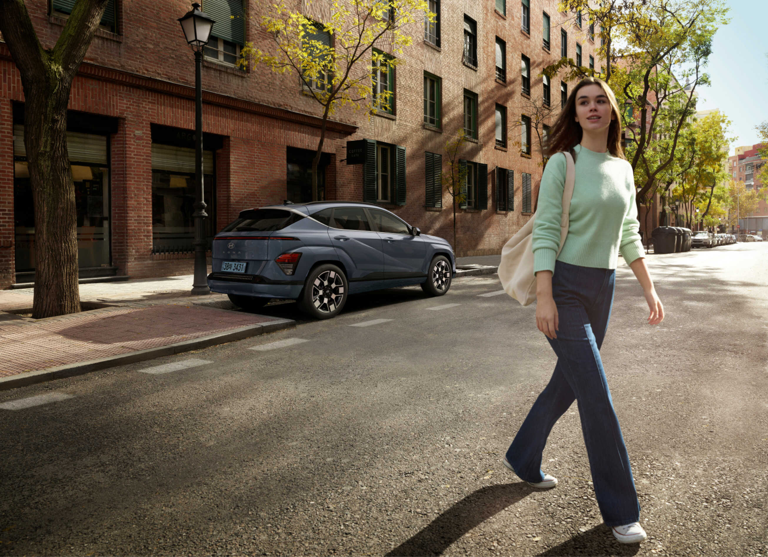 주차되어 있는 디 올 뉴 코나 일렉트릭 앞으로 사람이 걷고 있는 모습