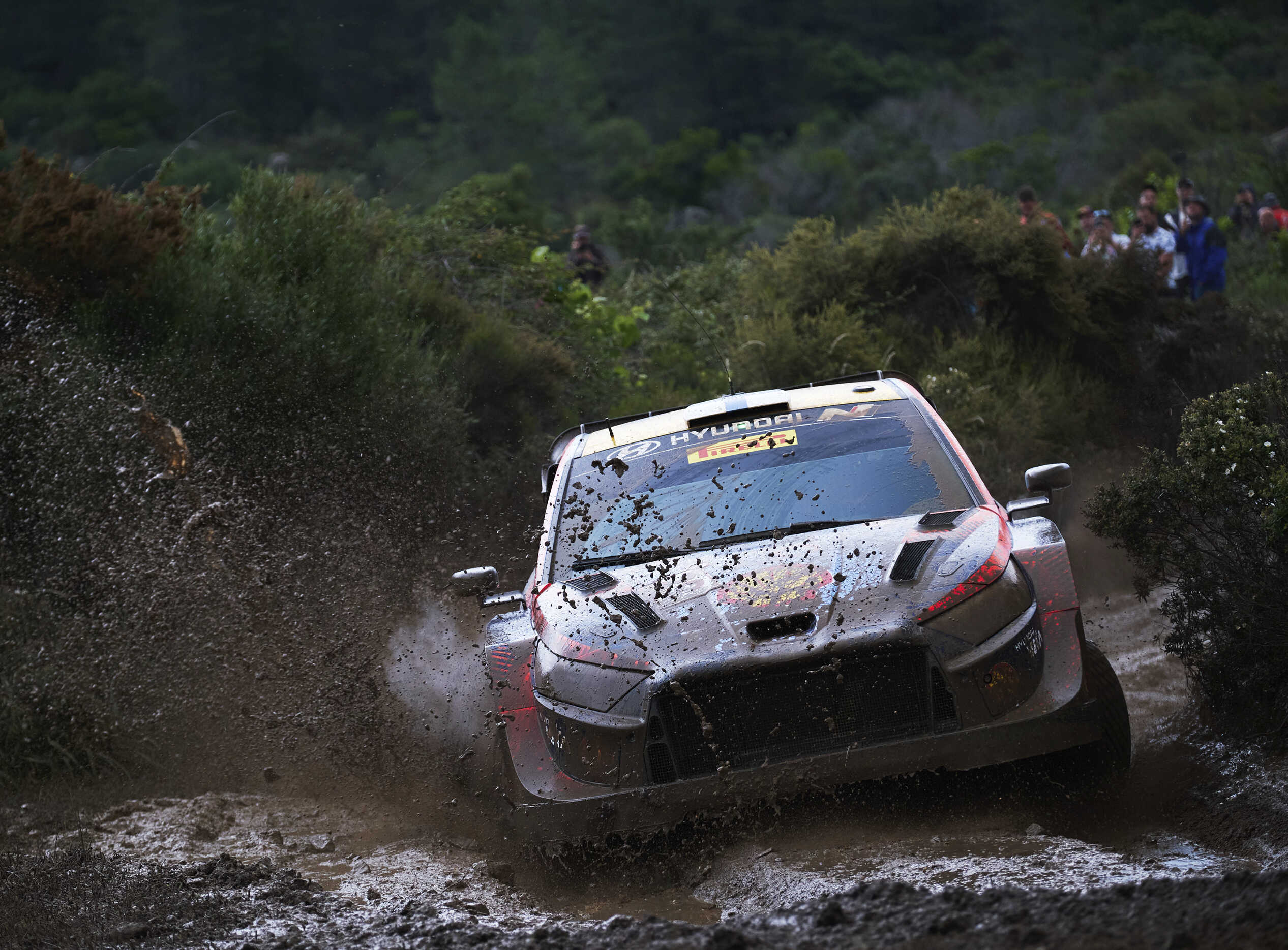 A Hyundai rally car running through mud in the rain