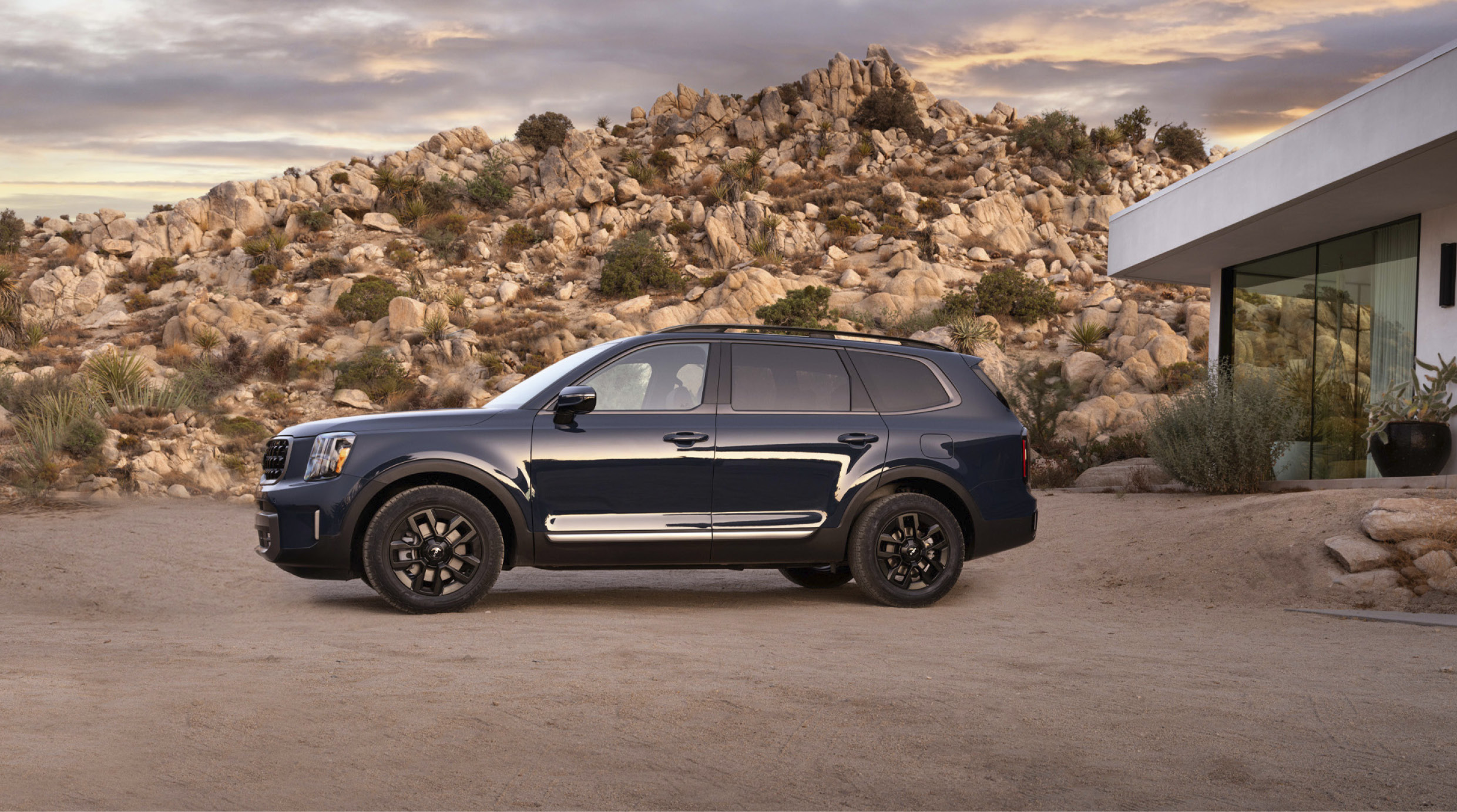 기아 텔루라이드 X-프로가 사막과 주택을 배경으로 주차된 모습