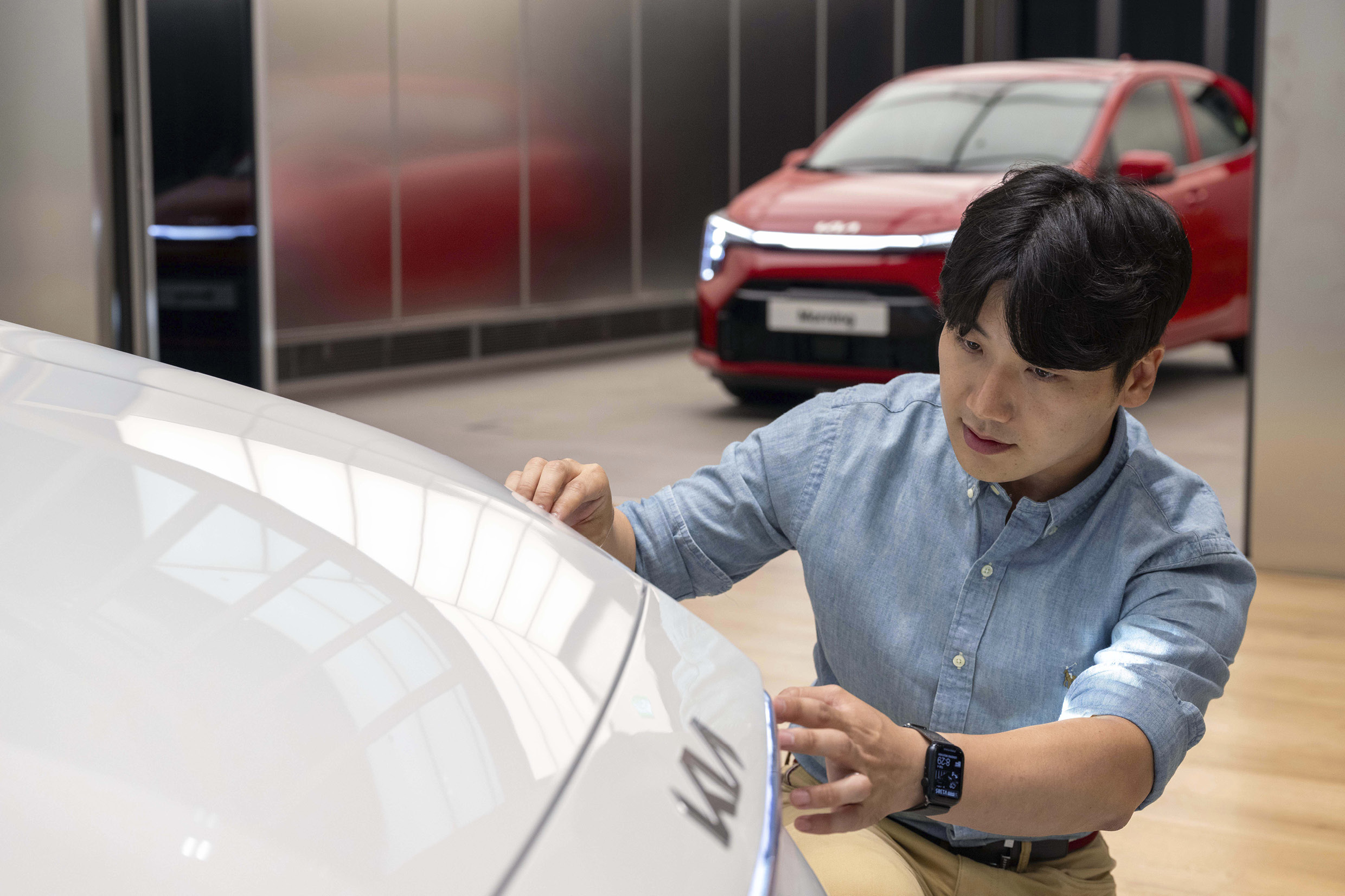 모닝 전면부를 앉아 살피는 남자의 모습