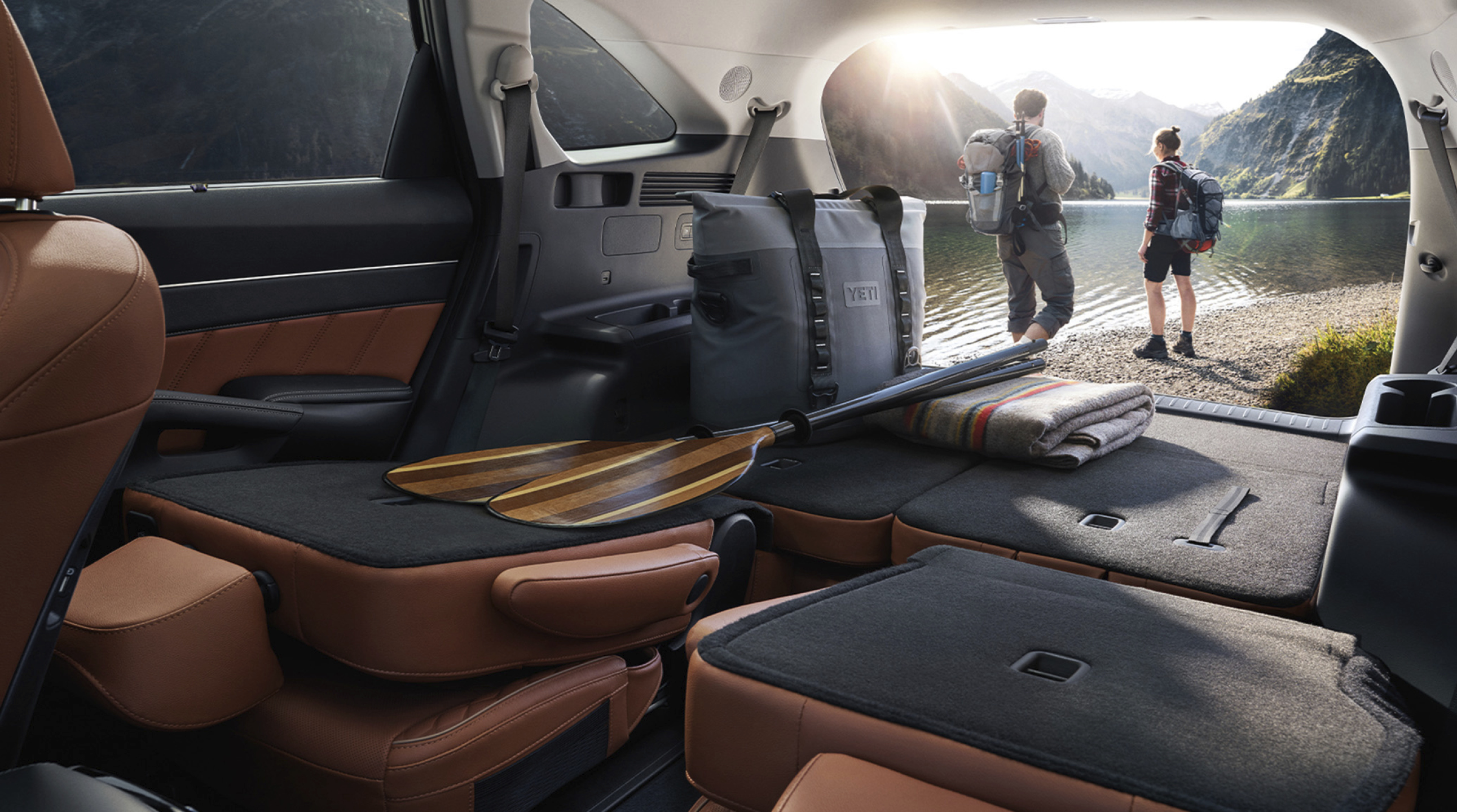 2열 시트를 접은 적재공간 너머로 성인 남녀 두 명이 포즈를 취한 모습