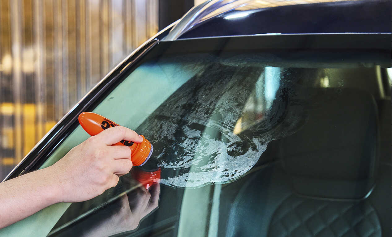 A man applying rain repellent to the windshield