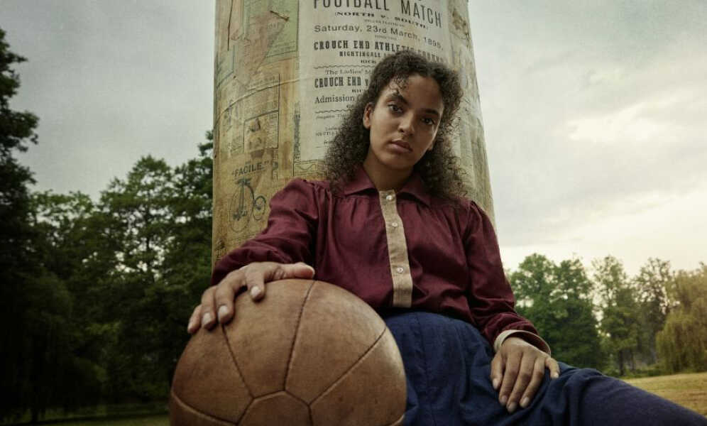 한 여성이 축구공에 손을 얹은 채 앉아 있다