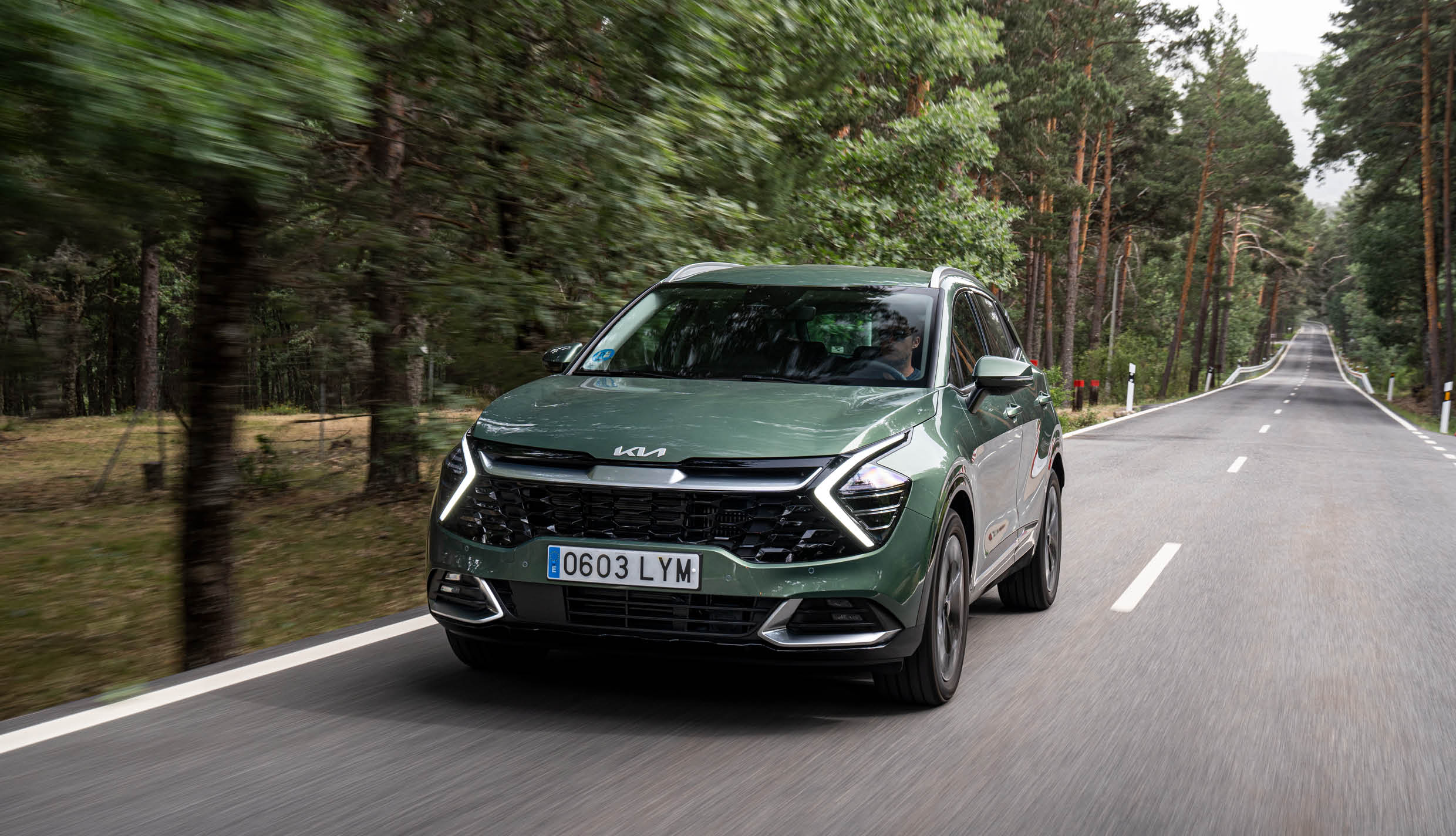 스포티지가 숲길을 주행하는 전측면 모습