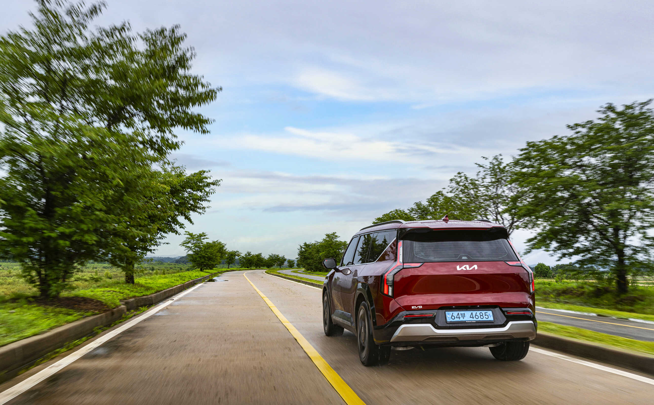 A red EV9 on a two-lane road