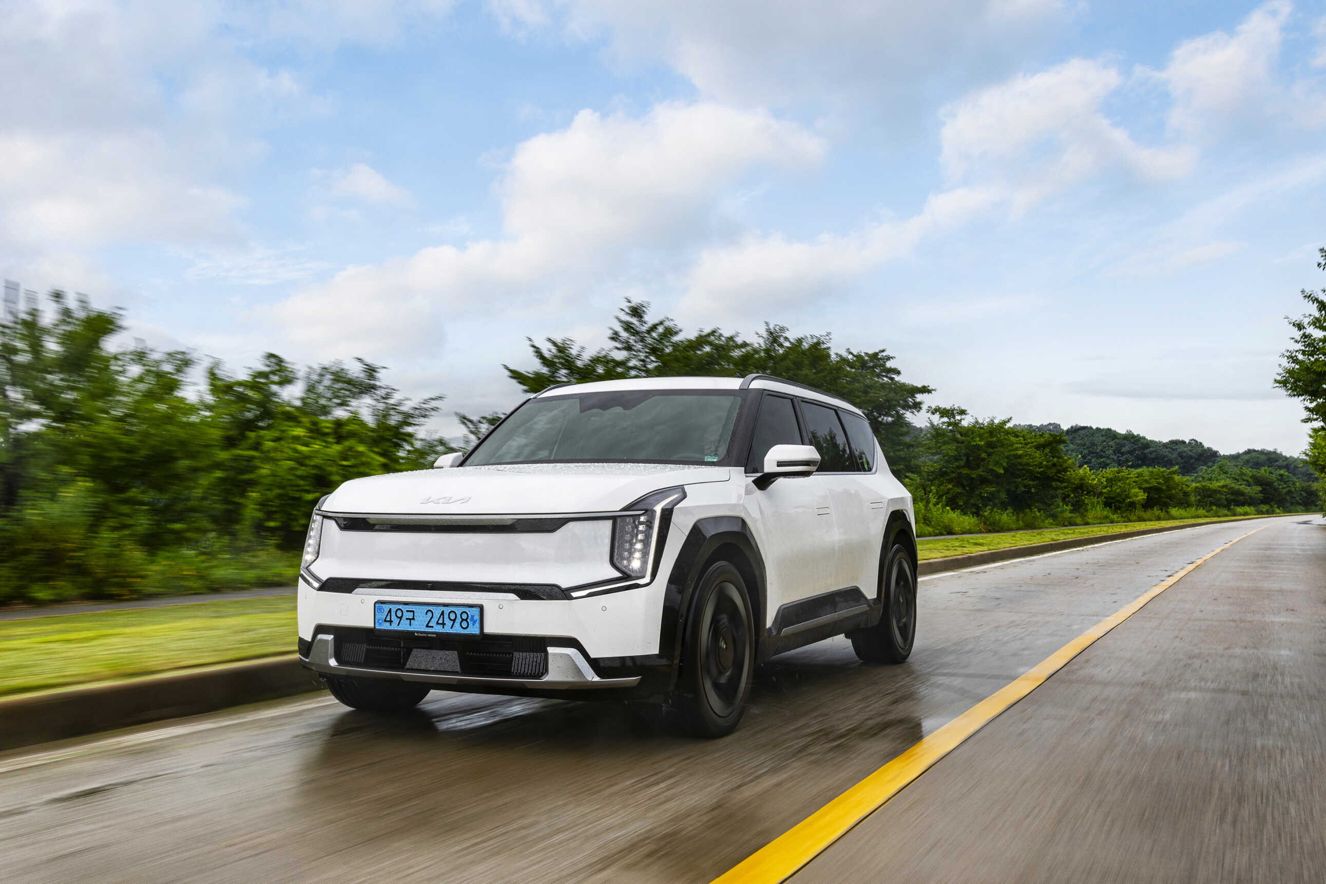 A white EV9 on a two-lane road