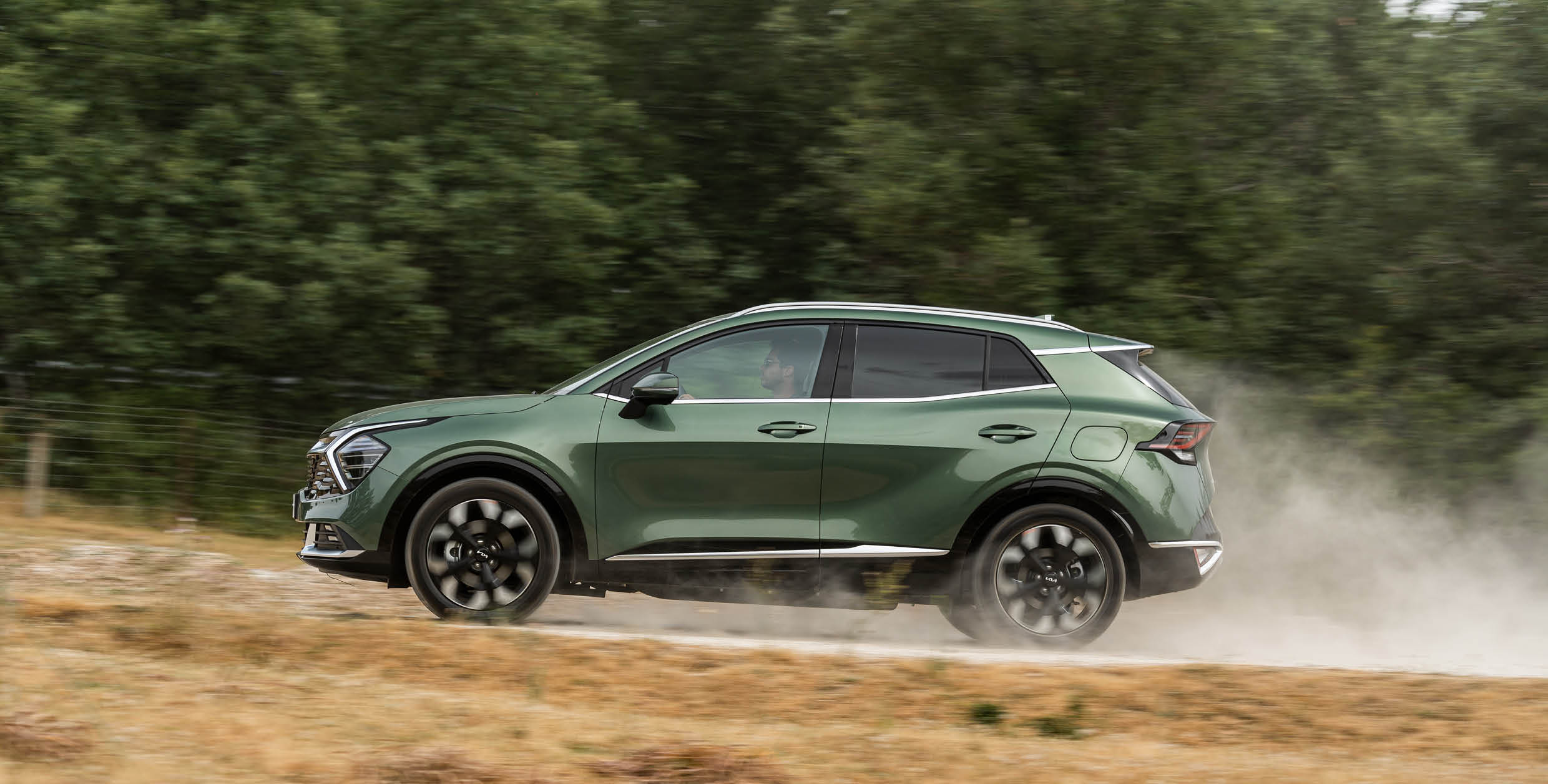 스포티지가 흙길을 주행하는 측면 모습