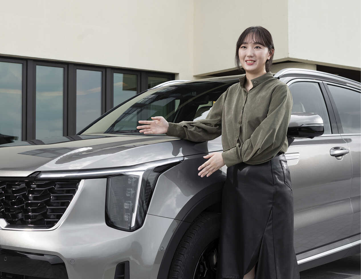 A woman explaining with her arms stretched out next to The New Sorento