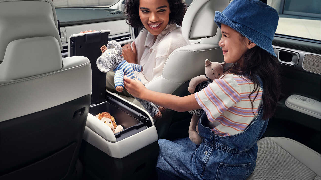 A woman and a child holding a doll in a Hyundai The All New Santa Fe