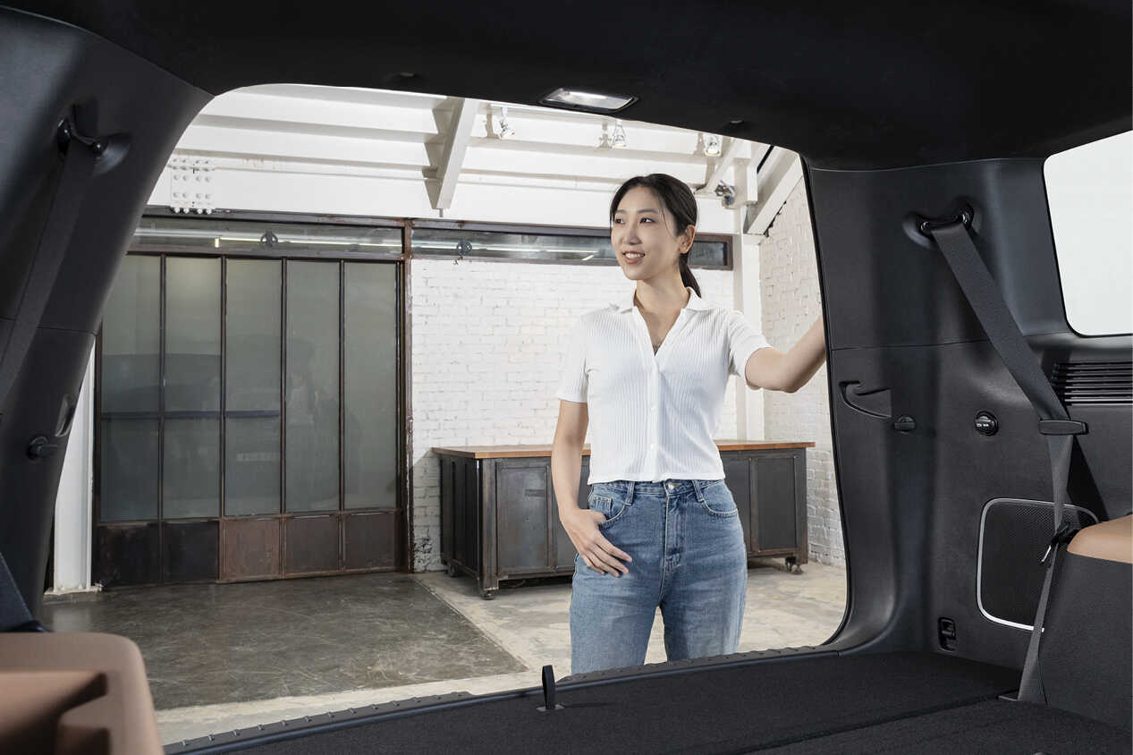 An interior designer is standing with his hand on the rear of the Hyundai The All New Santa Fe.