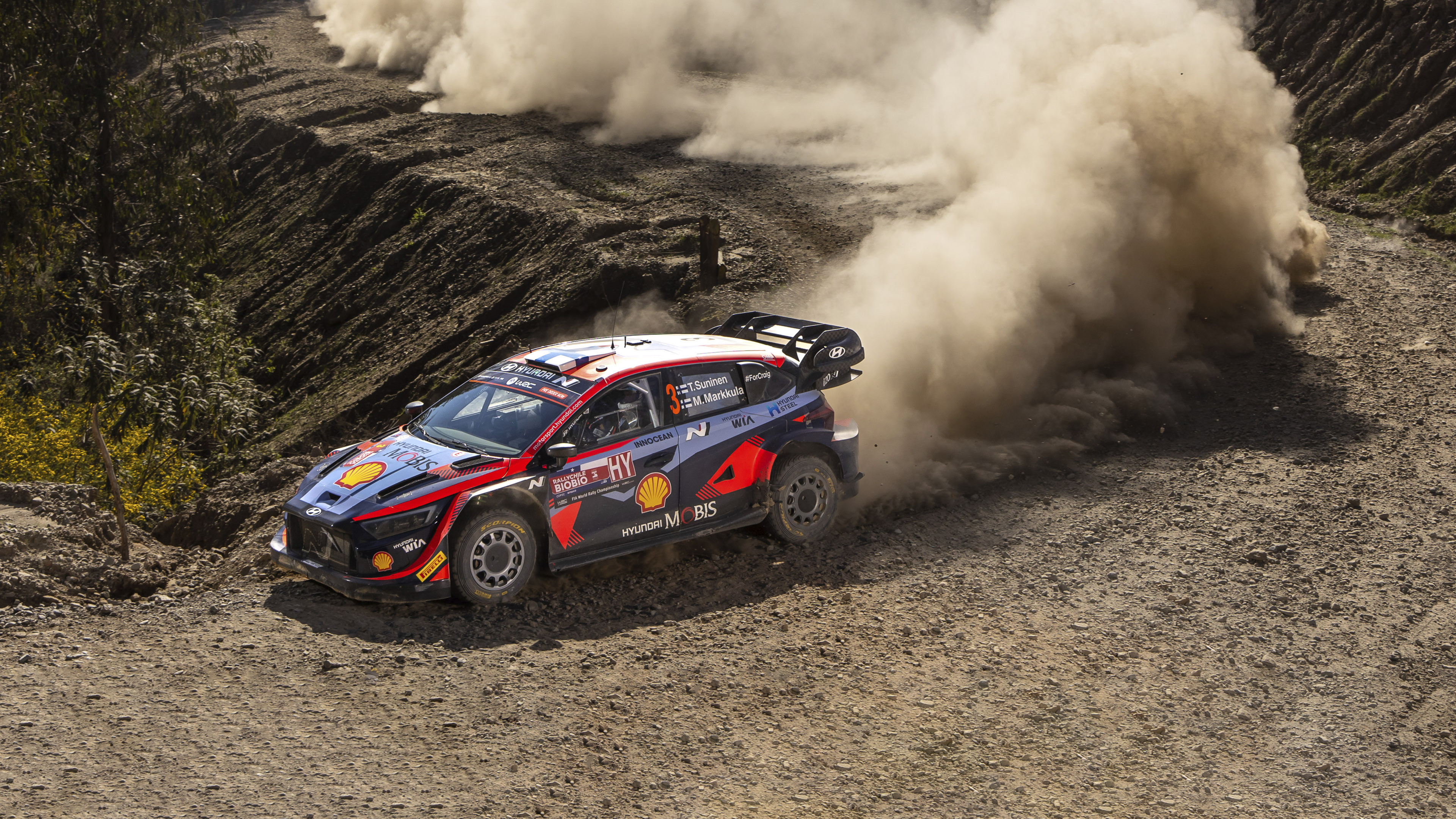 A Hyundai rally car is racing down a rough road.
