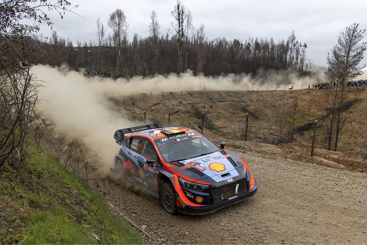 A Hyundai rally car is racing down a rough road.