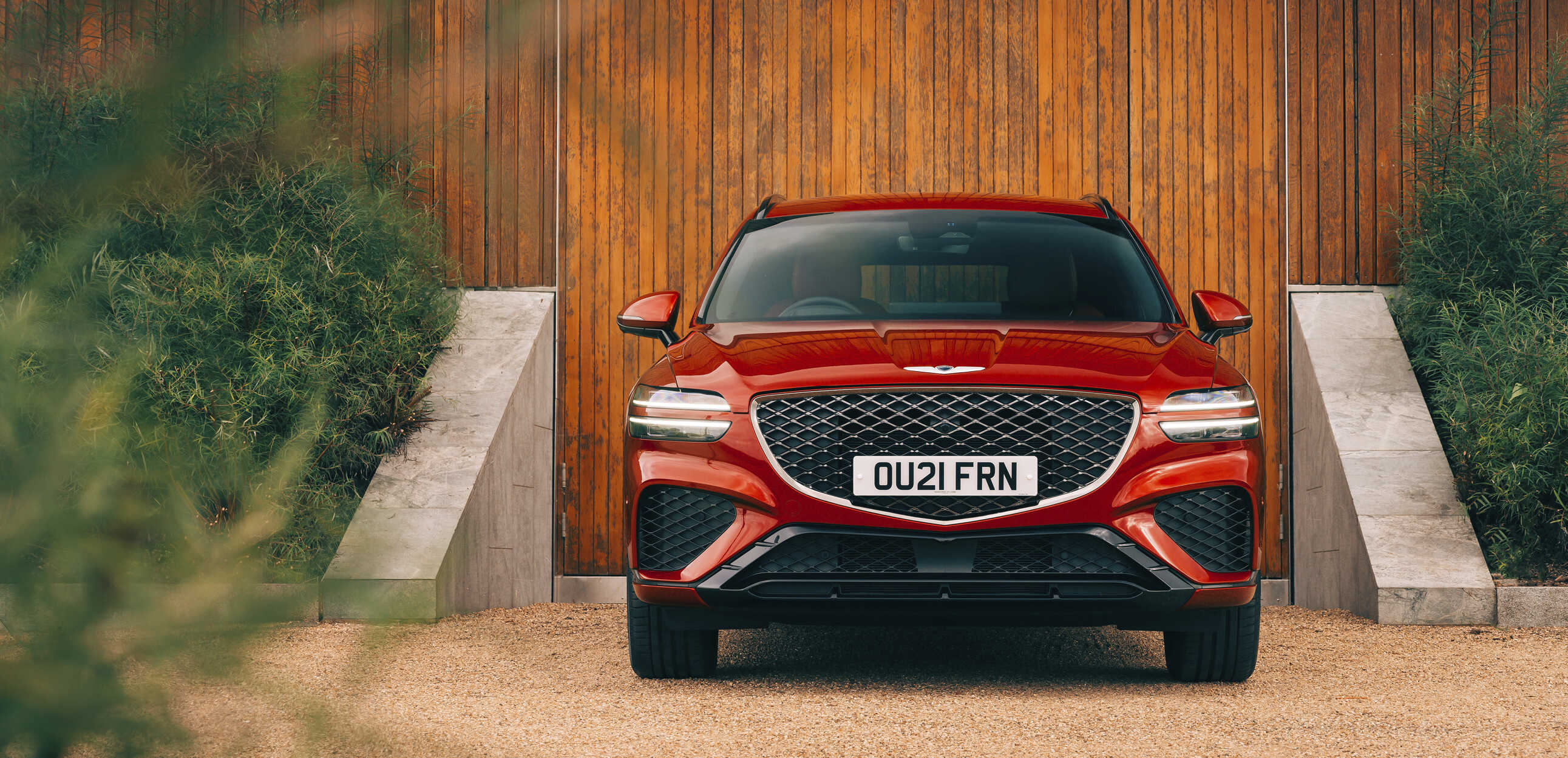 제네시스 GV70가 나무벽을 배경으로 서 있는 모습