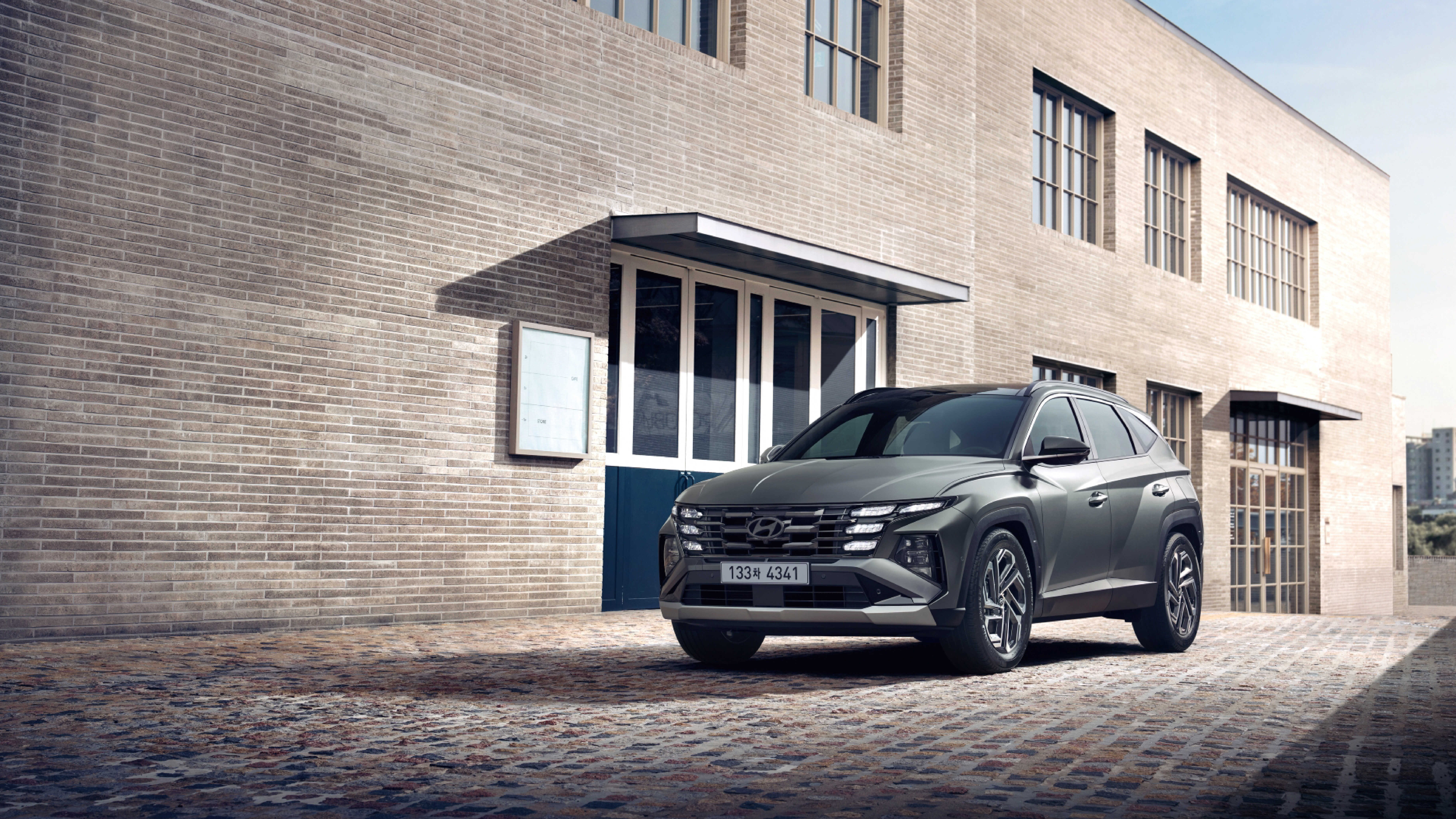 모던한 건물 앞에 서 있는 더 뉴 투싼