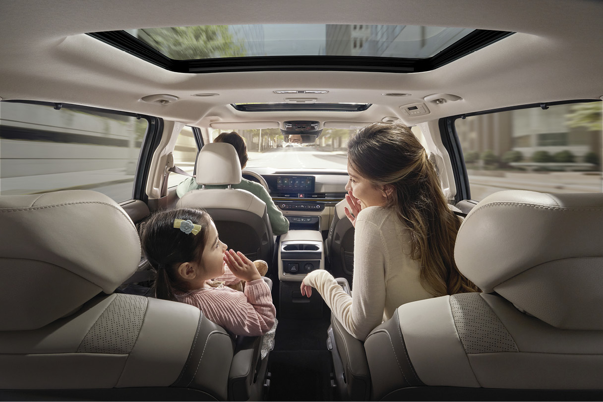 People riding in the back seat of Kia The New Carnival Hybrid