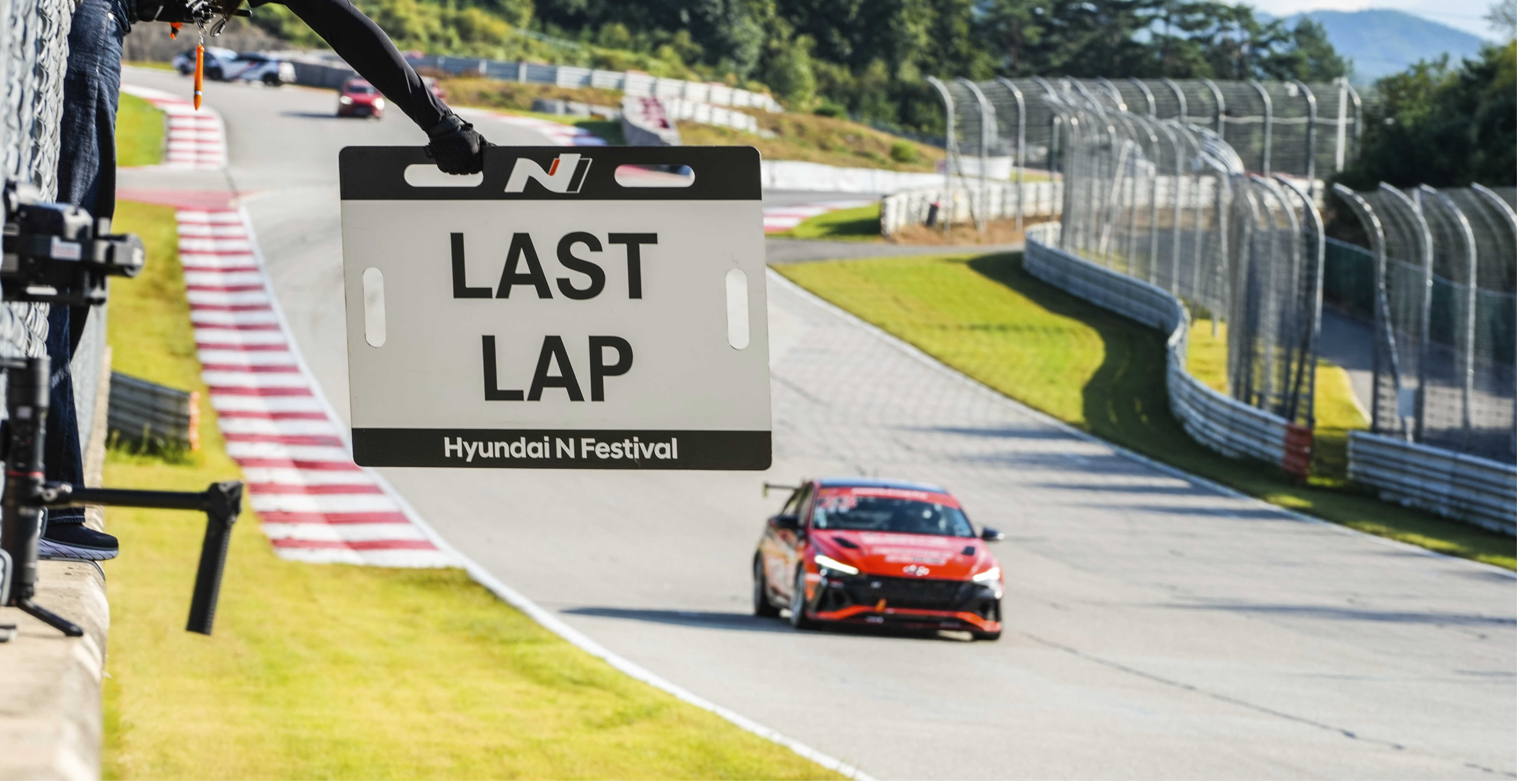 A sign announcing the last lap and a race car wrapped in red