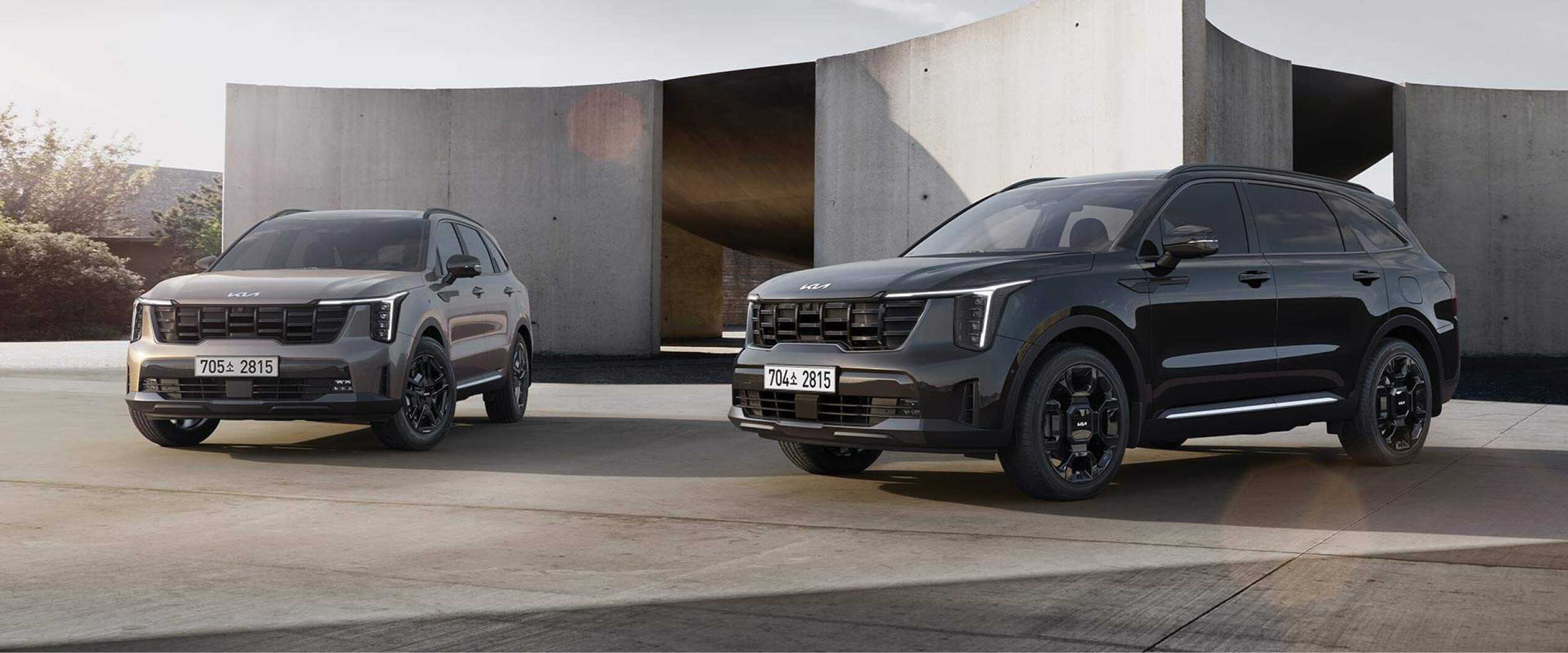 A pair of Kia SORENTOs, one in black and the other in light brown