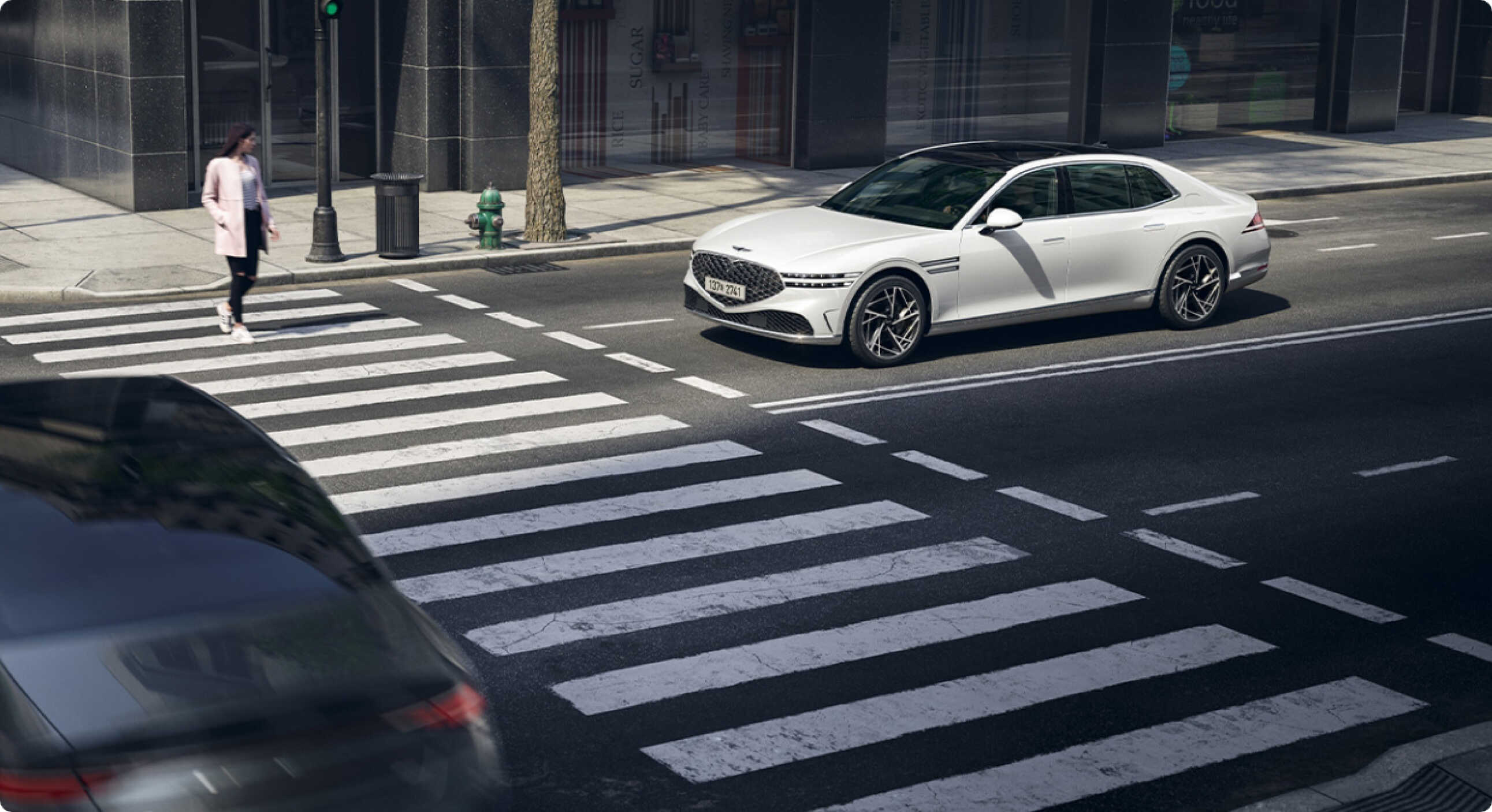 횡단보도를 건너는 사람을 위해 서 있는 제네시스 G90