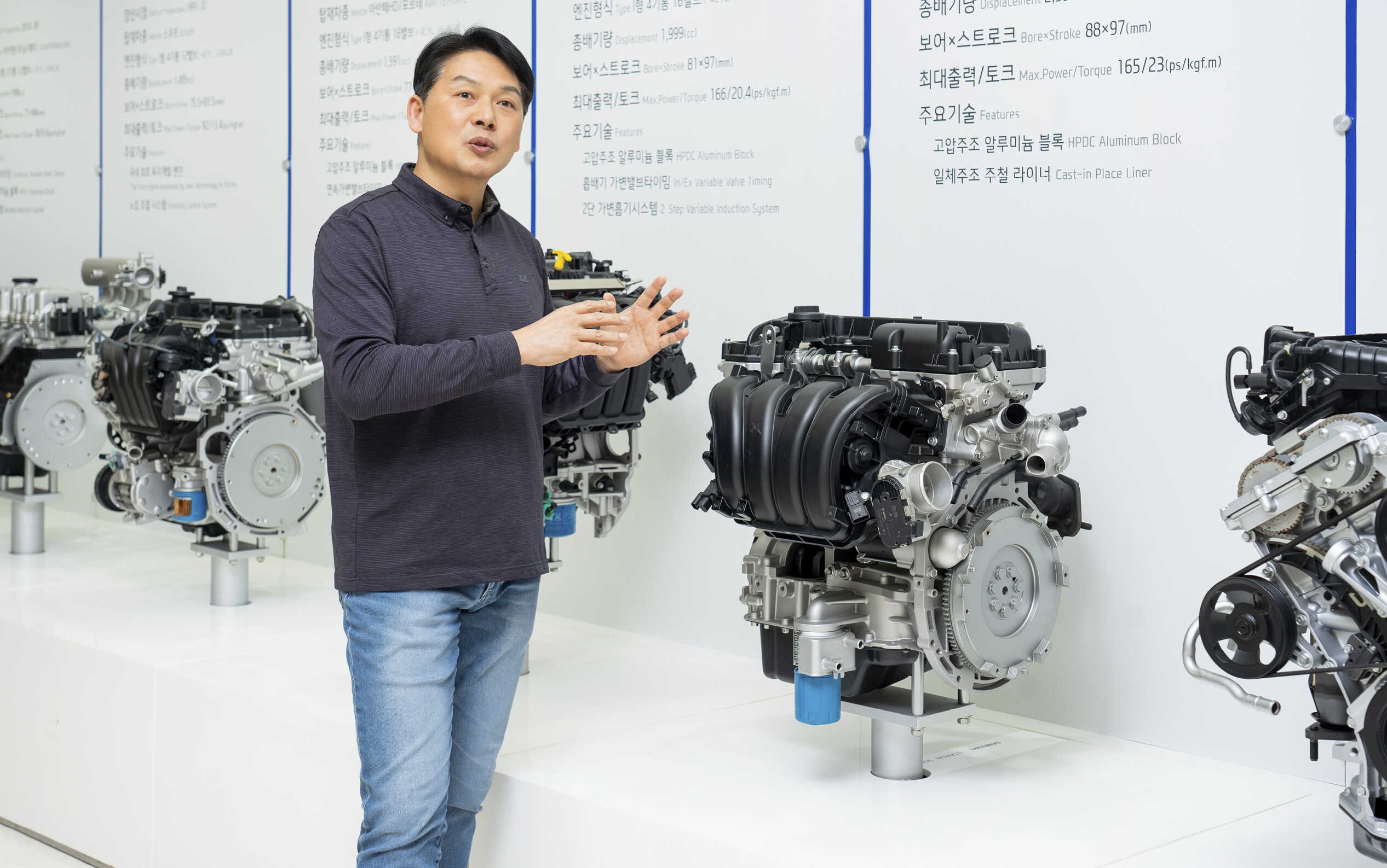 성인 남성이 엔진 옆에 서 팔을 들고 설명하는 모습 모습