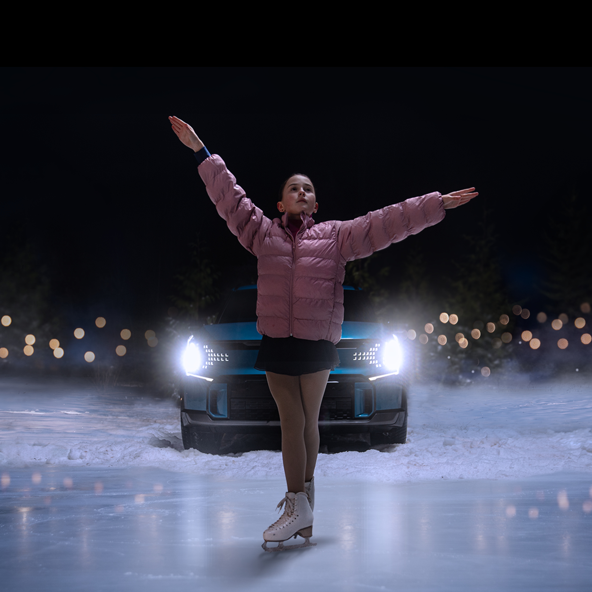 A girl spreading her arms wide and posing on the ice alongside a car.