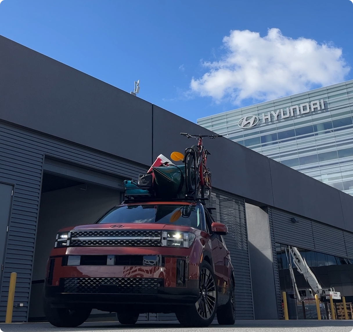 루프에 짐을 잔뜩 싣고 현대 건물 앞에 서있는 차량의 모습