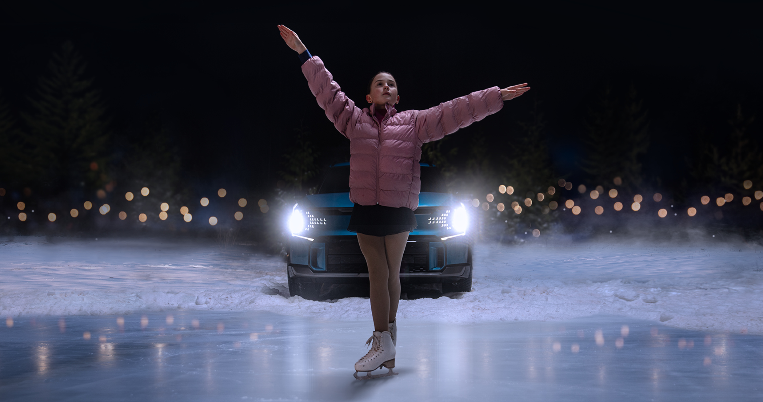 A woman spreading her arms wide and posing in front of a car.