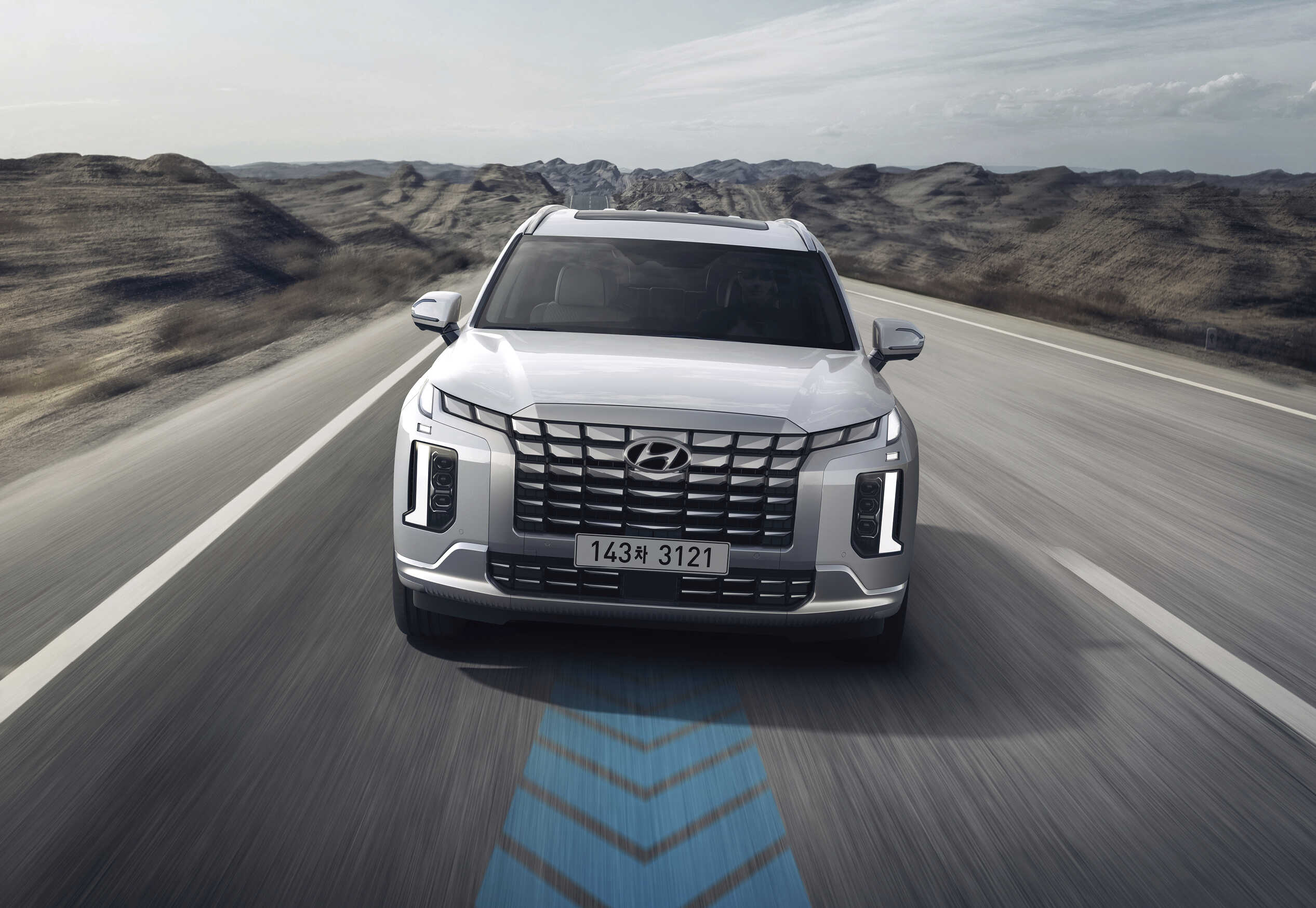 팰리세이드가 2차로 아스팔트 도로를 주행하는 정측면 모습