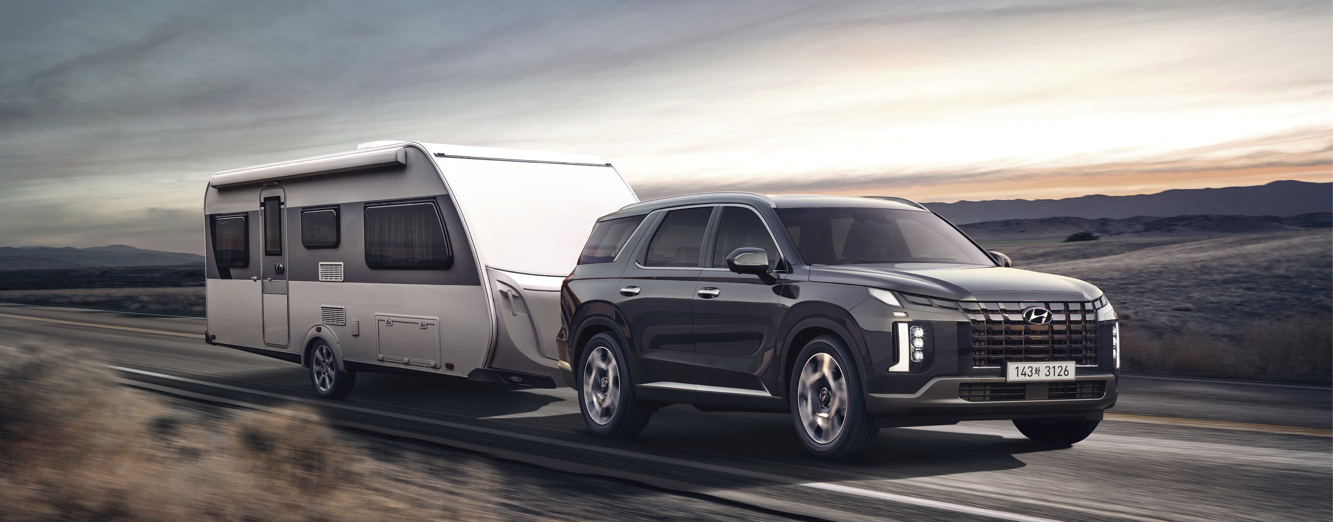 검은색 팰리세이드가 편도 1차로 아스팔트 도로를 카라반을 이끌고 주행하는 전측면 모습