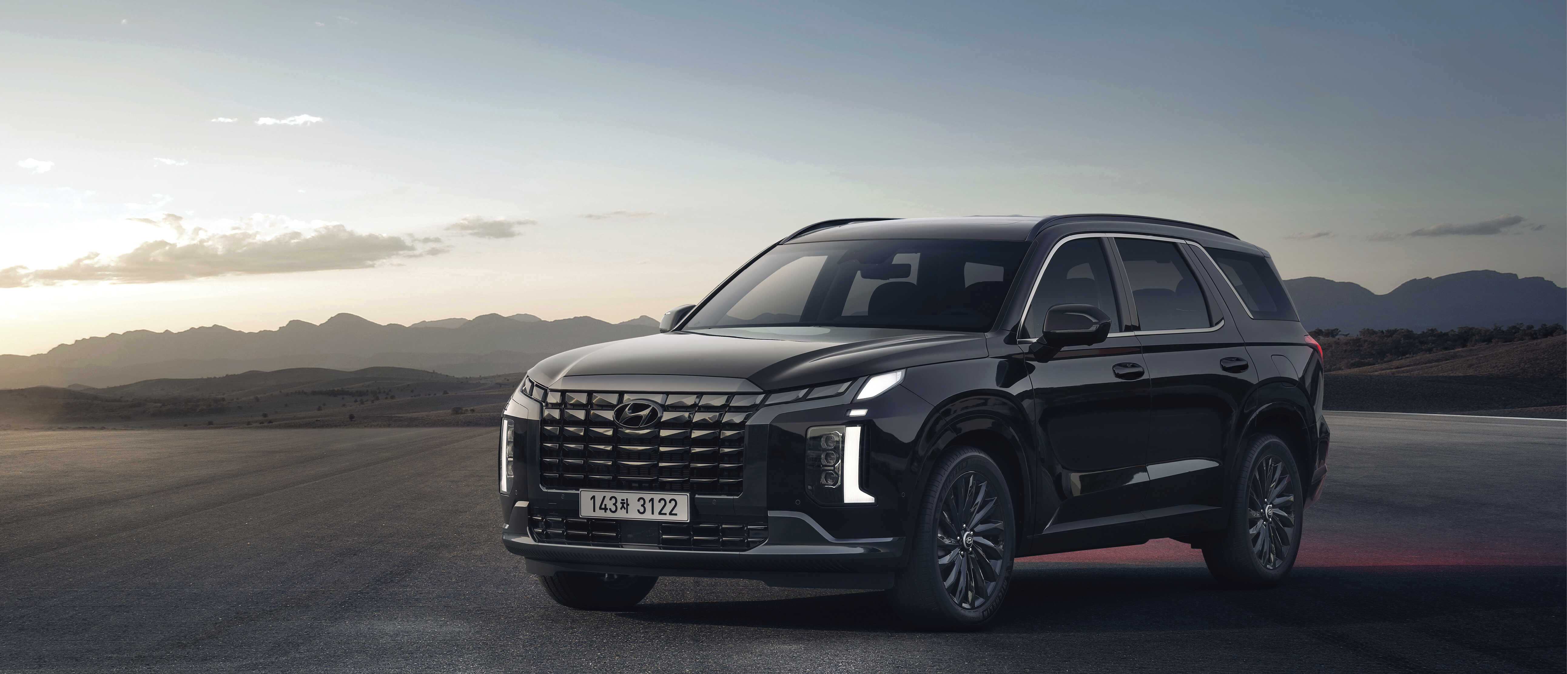 넓은 아스팔트 평야 위에 검은색 팰리세이드가 정차한 전측면 모습