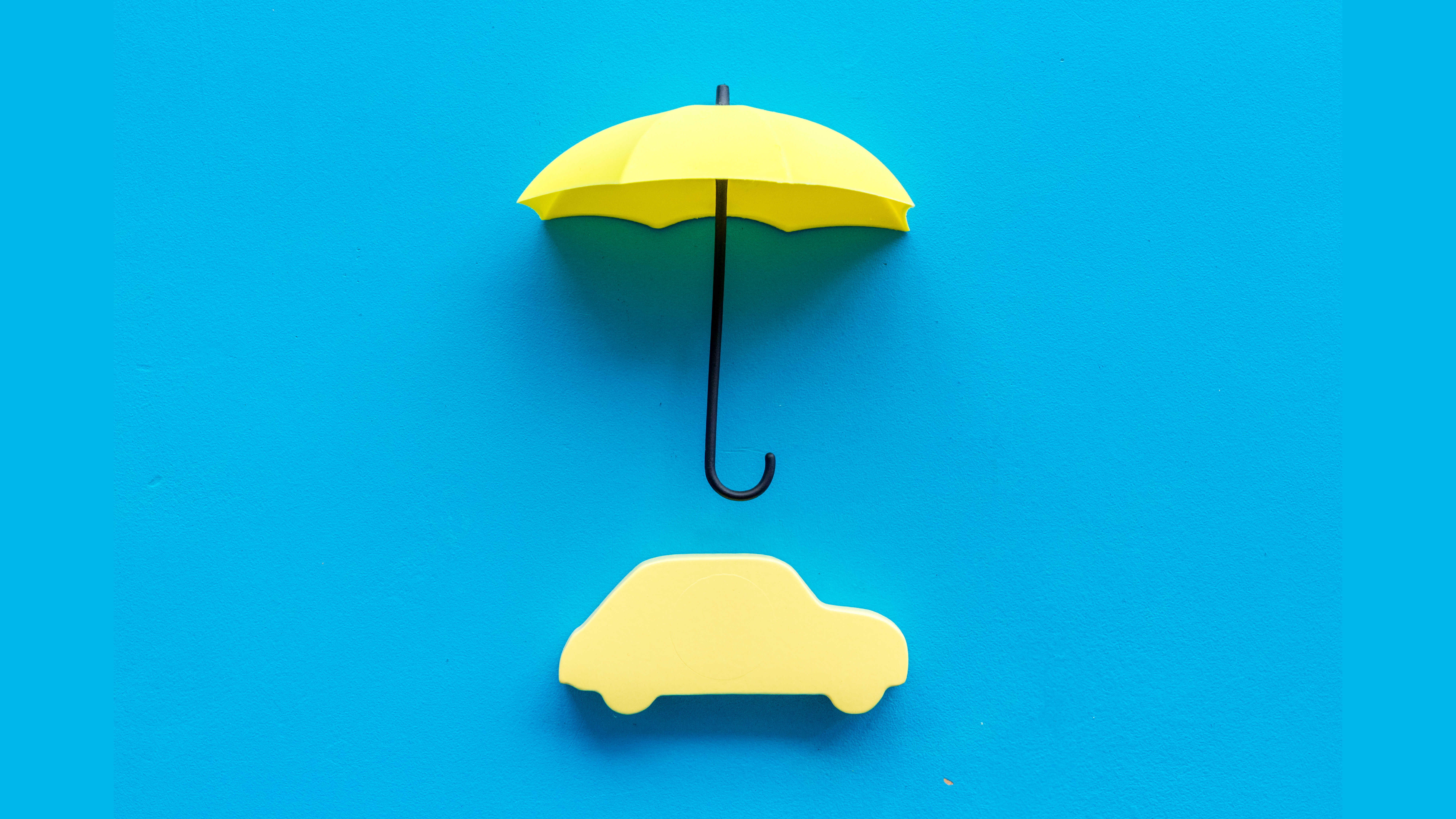 파란 배경 중심에 노란색 우산 모형과 자동차 실루엣 모형이 위 아래로 배열된 모습