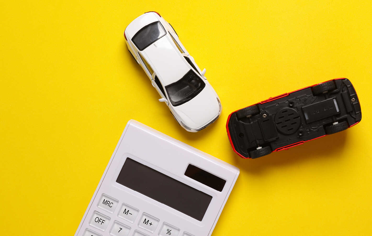 노란색 배경 위에 흰색 차 1대와 뒤집어진 빨간색 차 1대가 사선으로 배치돼있고 흰색 계산기가그 옆에 자리한 모습
