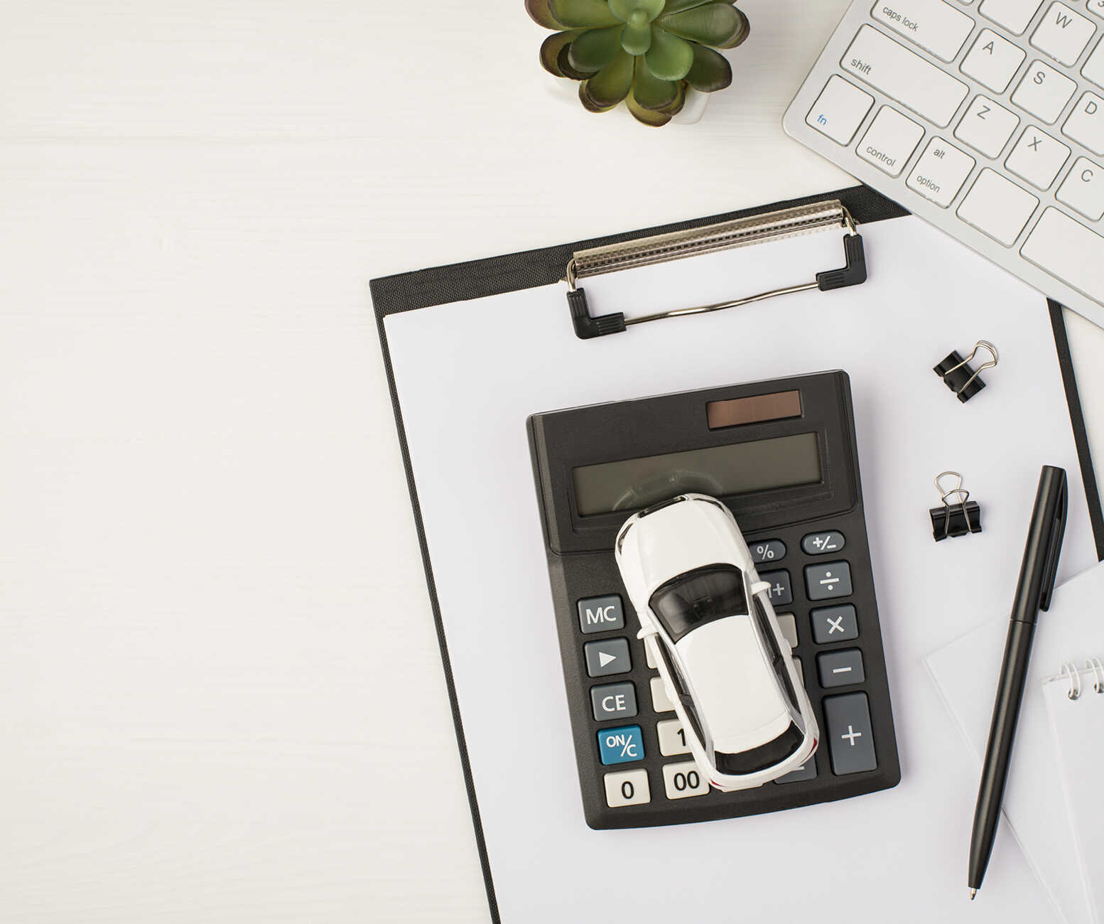 흰색 배경 위에 키보드, 화분, 계산기, 파일첩이 놓여 있는 모습