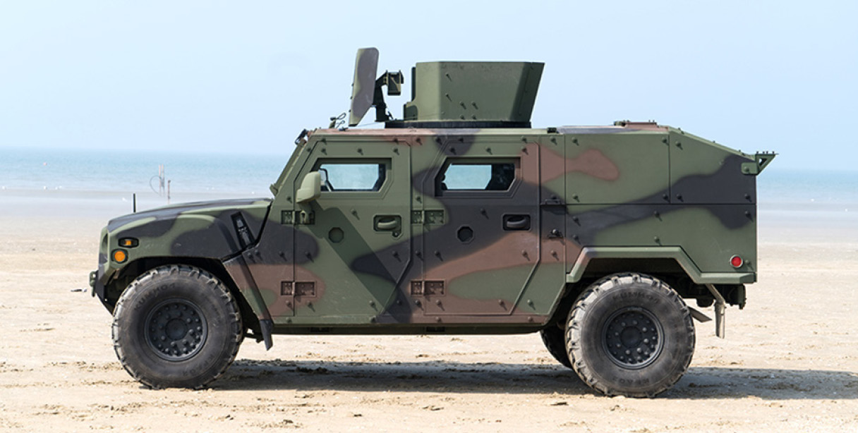 해변에 서 있는 기아의 소형전술차량 K153 기갑수색 차량의 옆모습